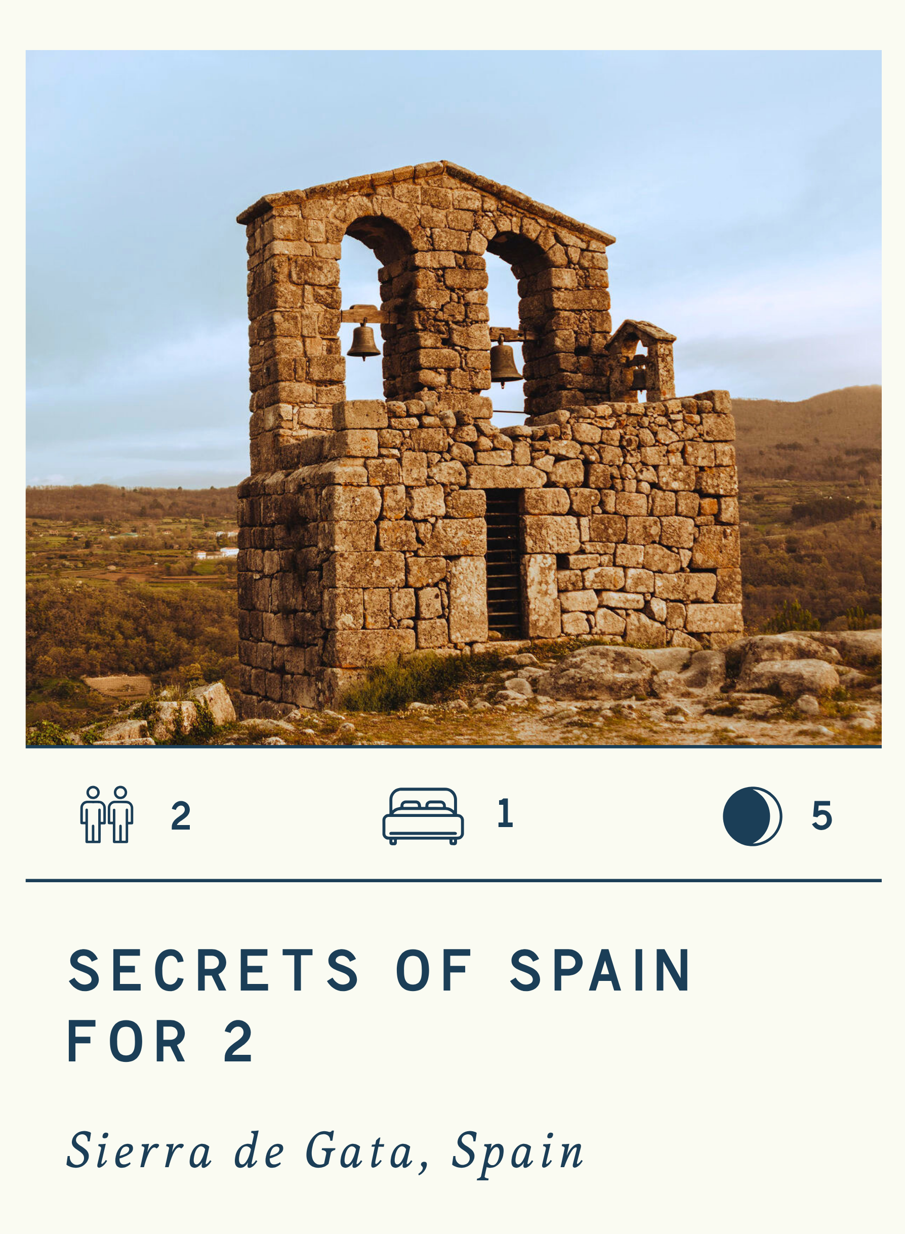 Ancient stone bell tower in Sierra de Gata, Spain, overlooking a rural landscape at sunset.