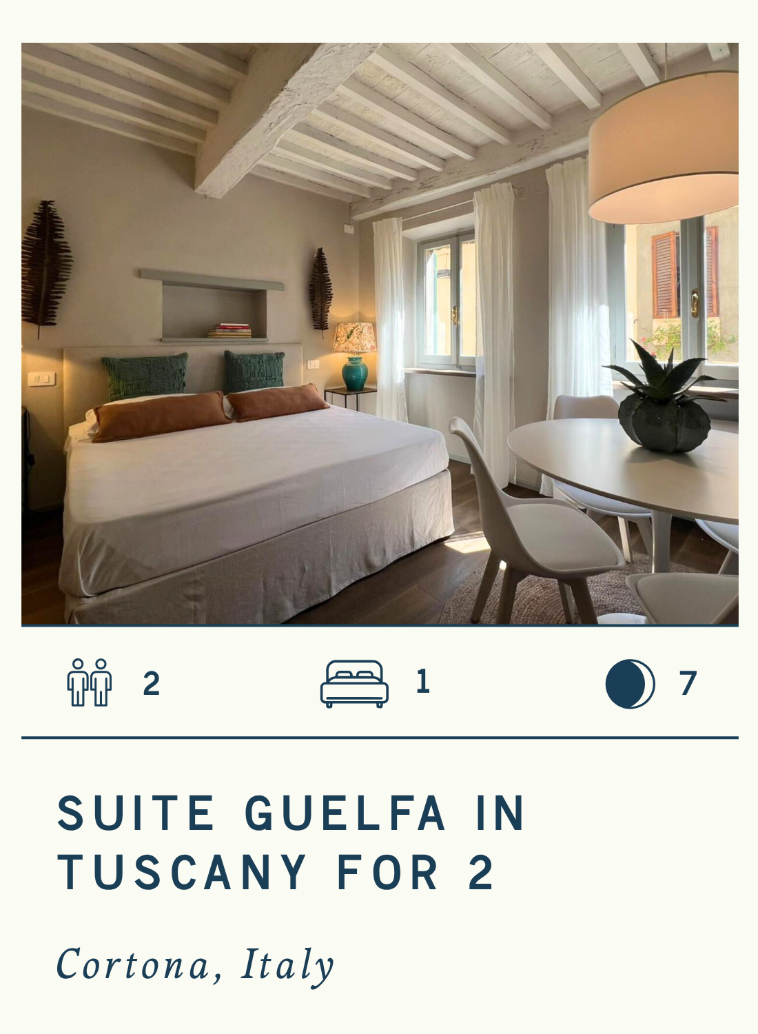 A cozy bedroom with a white bed, green pillows, a small table with a turquoise lamp, and windows with white curtains letting in natural light, with text describing a luxury suite in Tuscany for two.