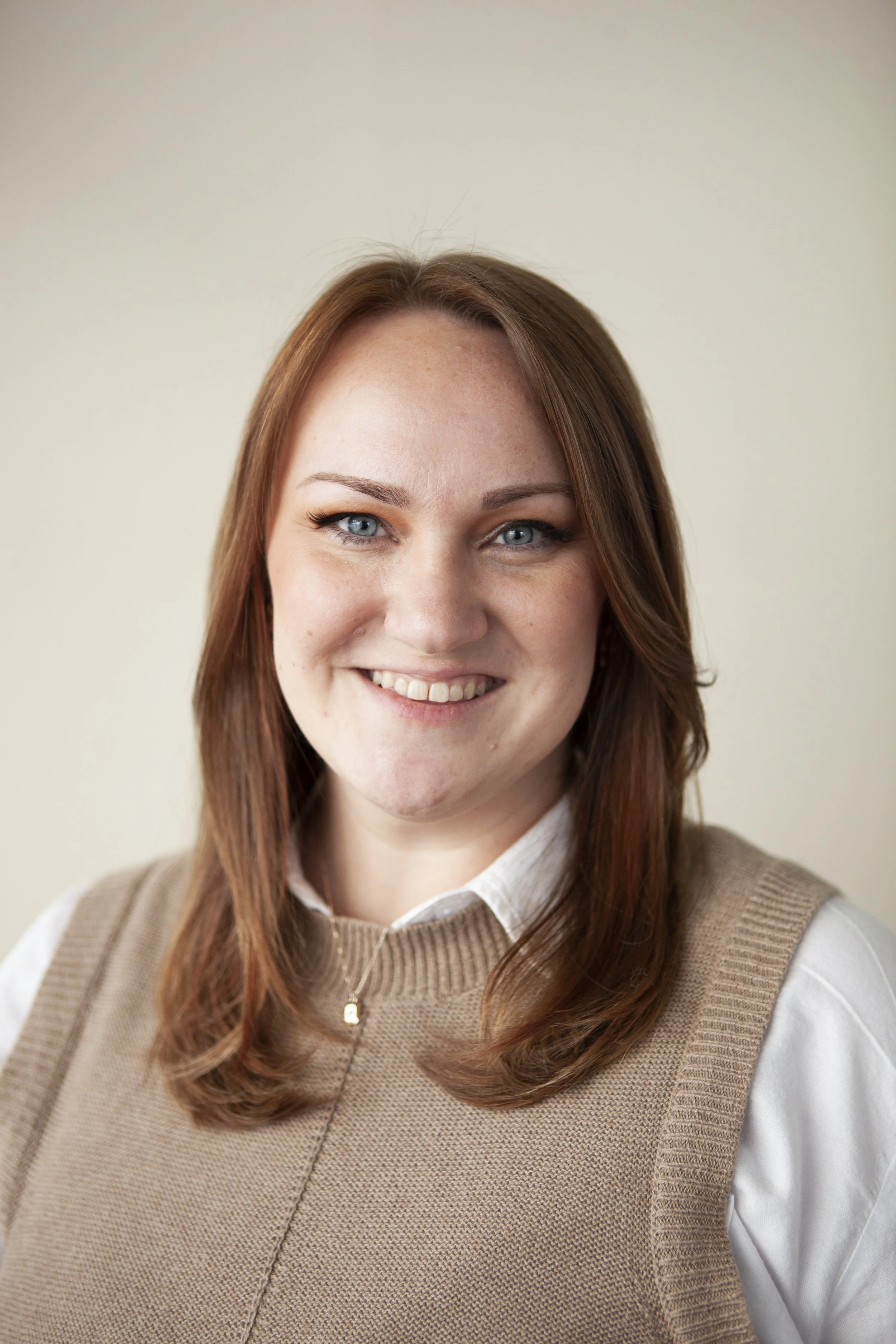 A woman with shoulder-length black hair smiling in a lush green indoor garden.