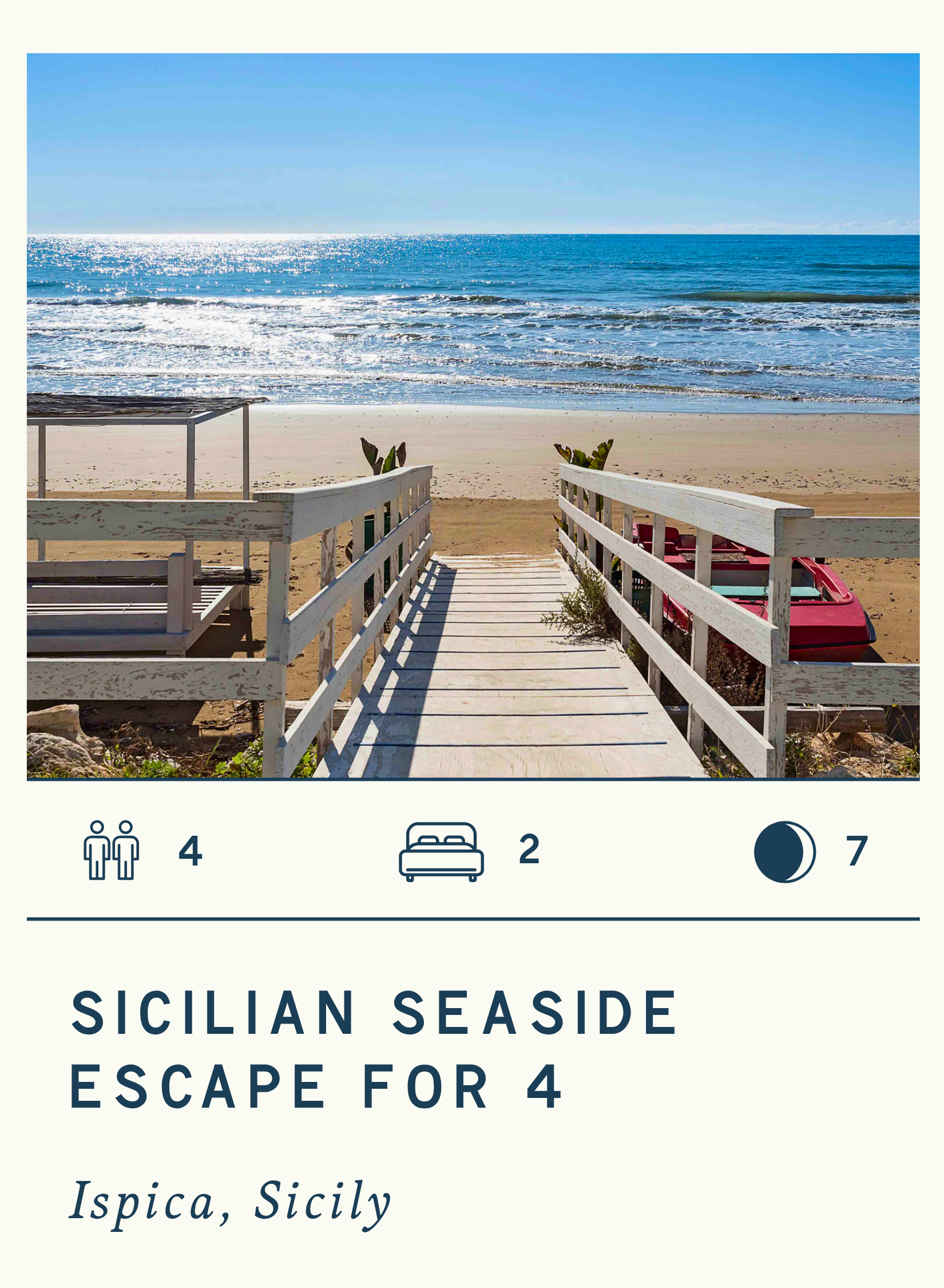 A beach scene with a wooden pathway leading to the shoreline, with a red paddle boat partially visible on the sand to the right, and the ocean with gentle waves and a clear blue sky in the background.