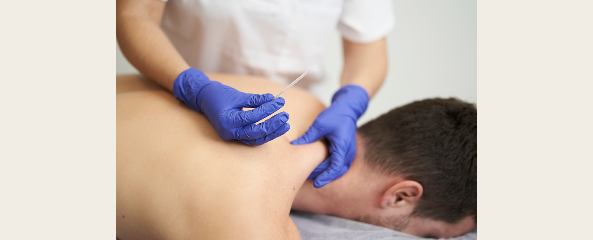A healthcare professional wearing blue gloves administering an injection into a person's shoulder.