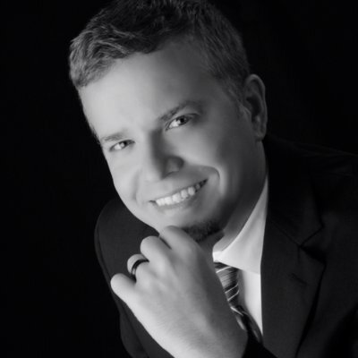 Black and white portrait of Ian Patton the CTO of InnoVet in a suit and tie, smiling with his hand resting on his chin.