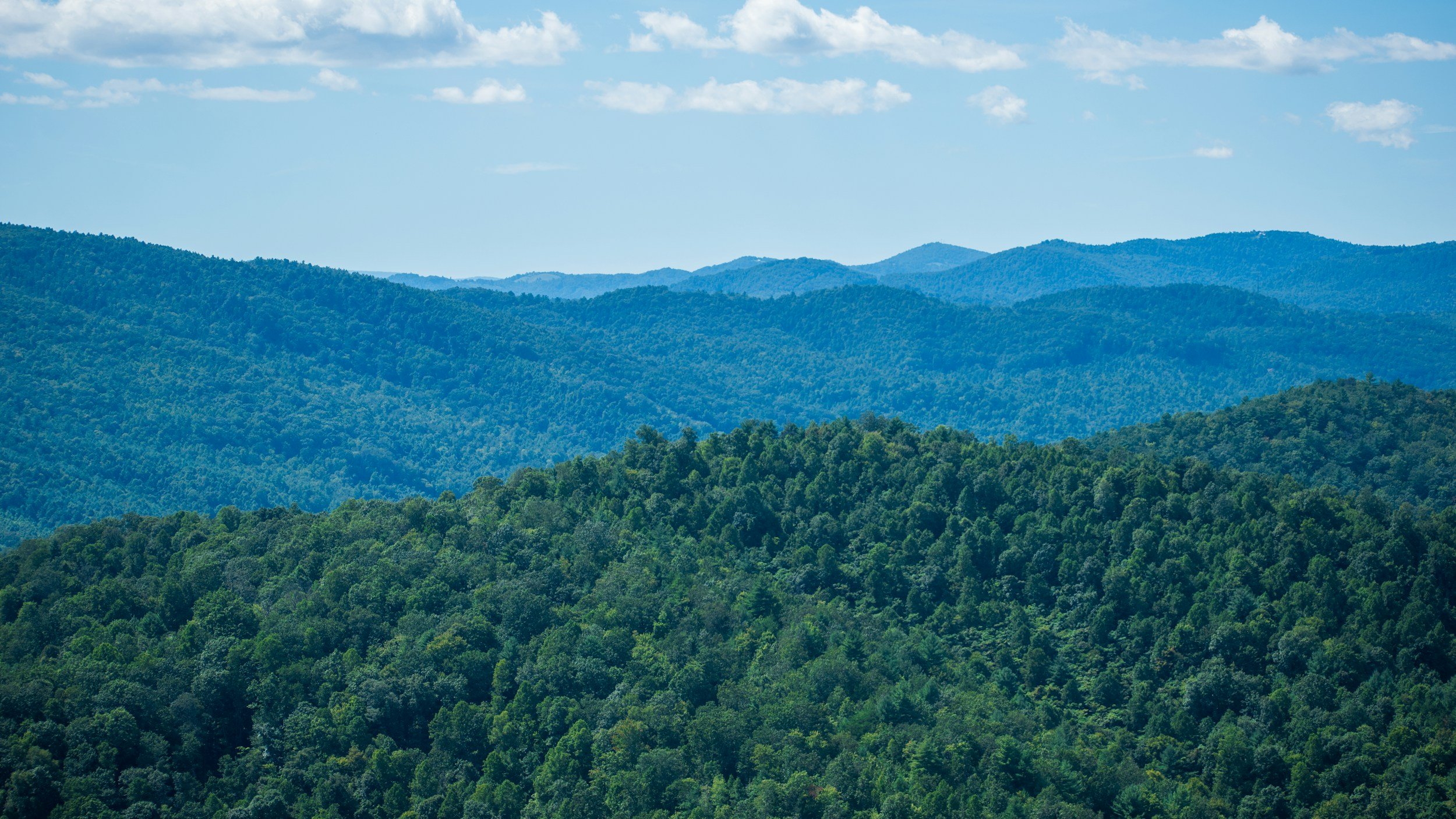 Green forested mountains under a partly cloudy sky.