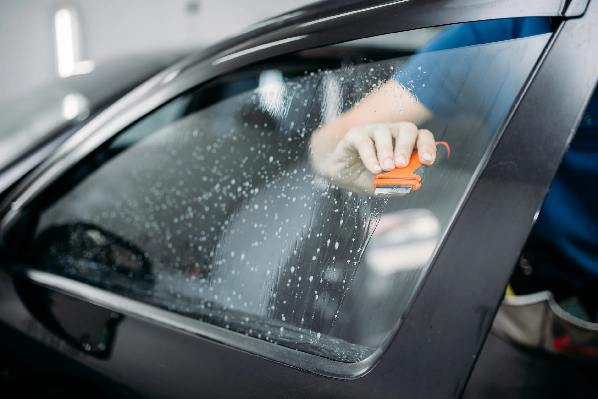 Person cleaning car window with squeegee.