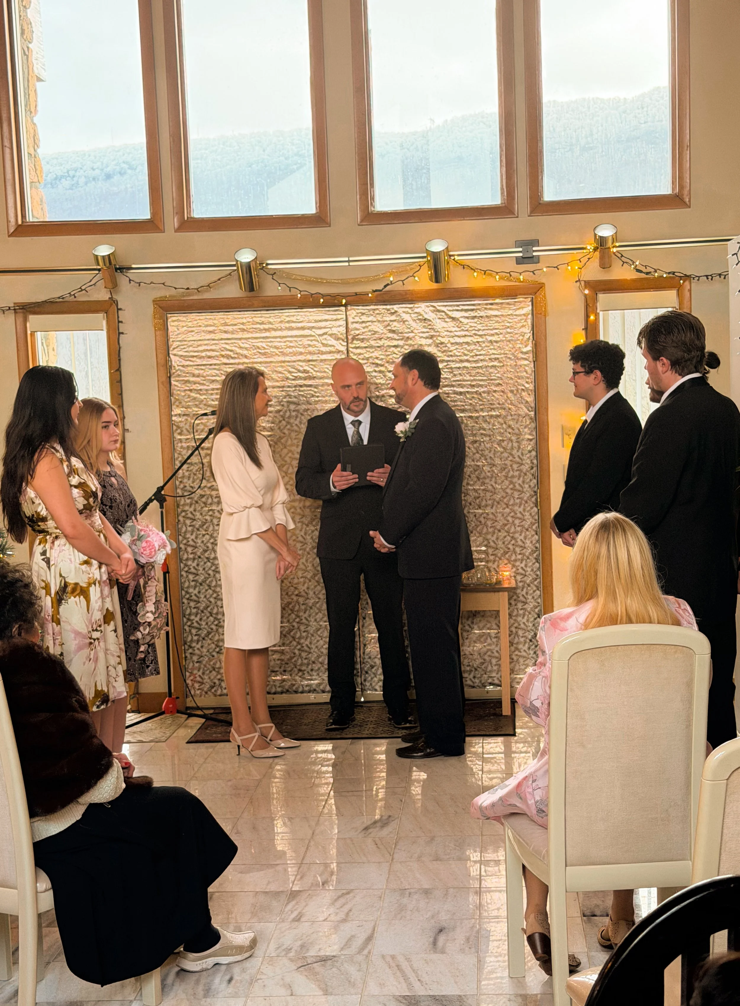 A bride and groom celebrating with sparklers surrounded by friends and family at a nighttime wedding reception outdoor celebration.