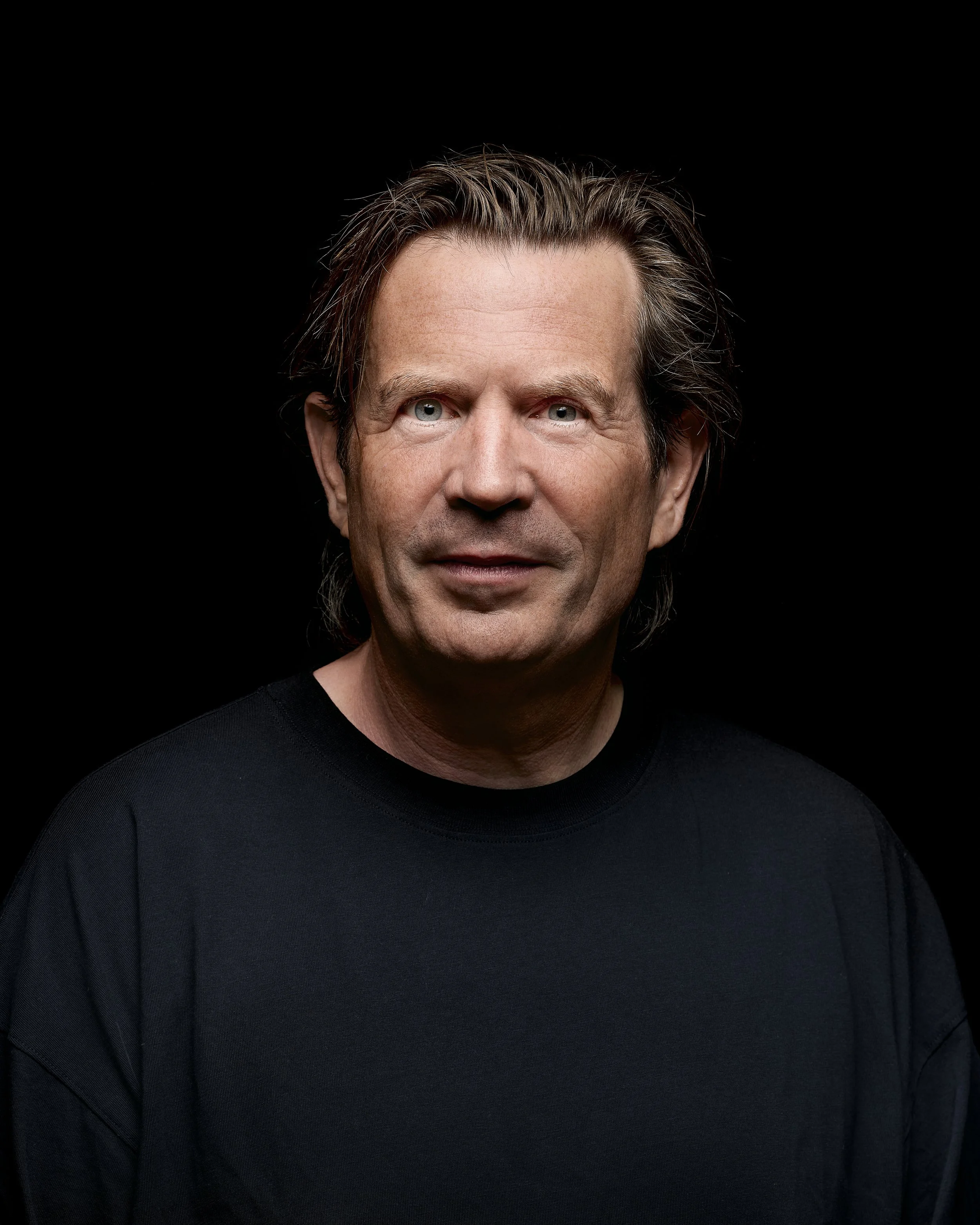 Artist Sebastiaan Hooft. A techno producer DJ performing on stage with DJ equipment, large screen displaying abstract graphics, and colorful stage lighting at night.