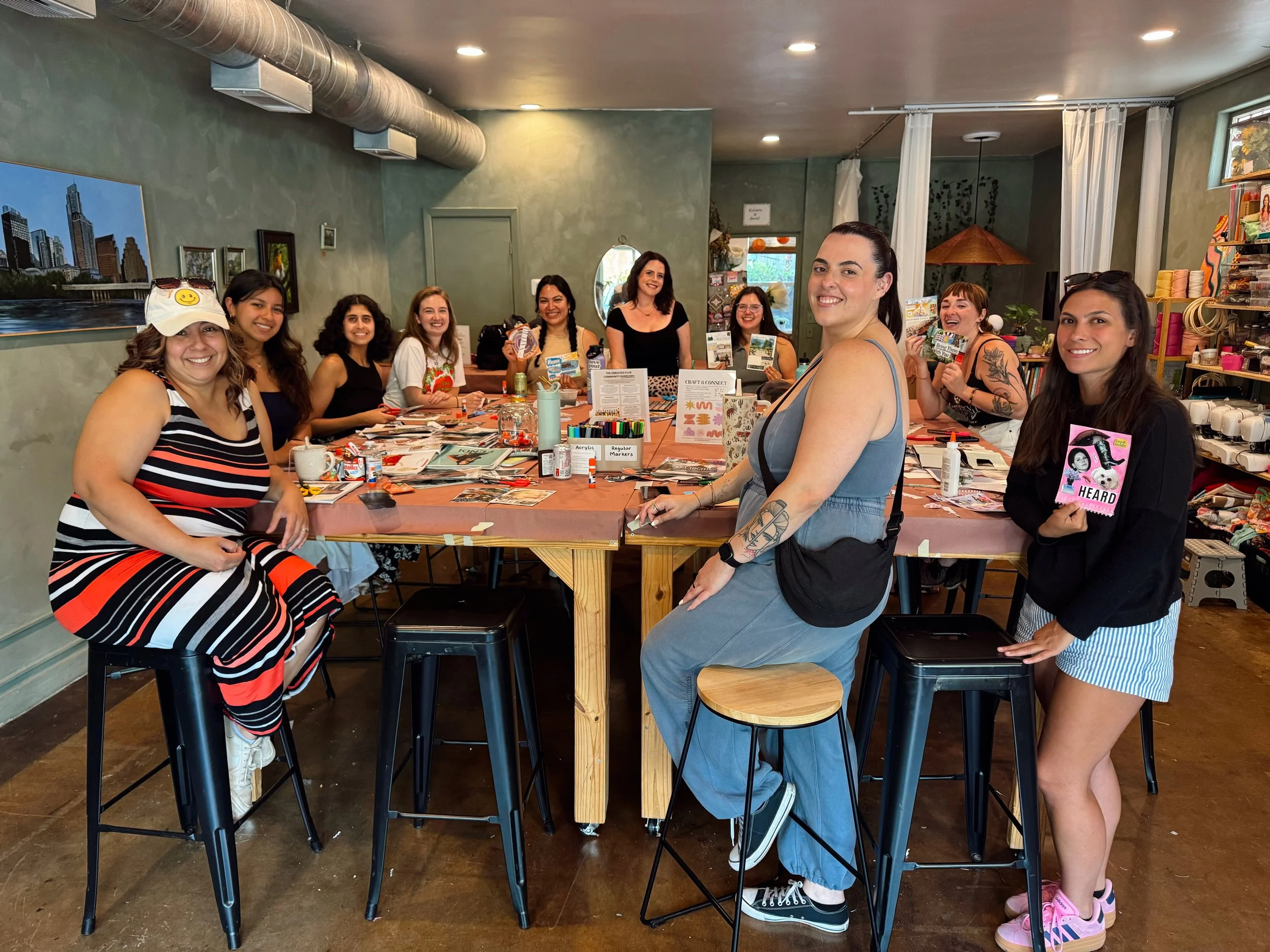 Group of women gathered around a craft table in a cozy, well-lit room, engaged in a crafting activity.
