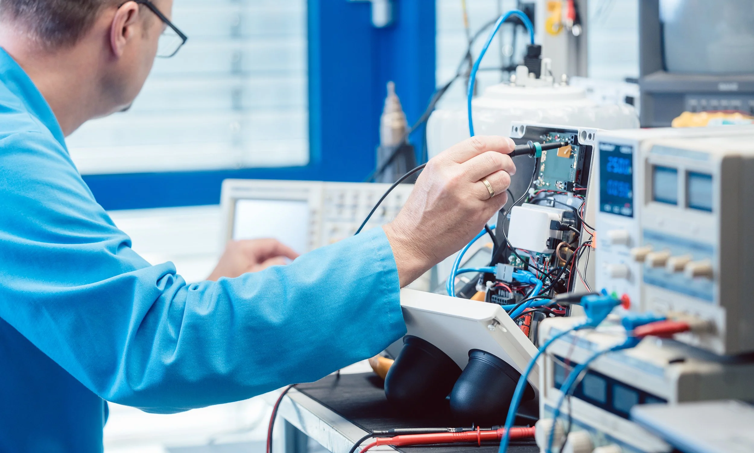 An engineer working with electronic equipment and testing devices on a workbench in a laboratory.