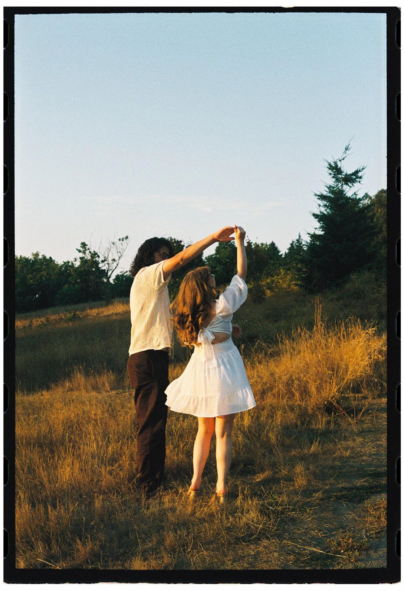 Engagement portrait of partners in a field at sunset, frolicing through the field at Discovery Park, Seattle, Washington