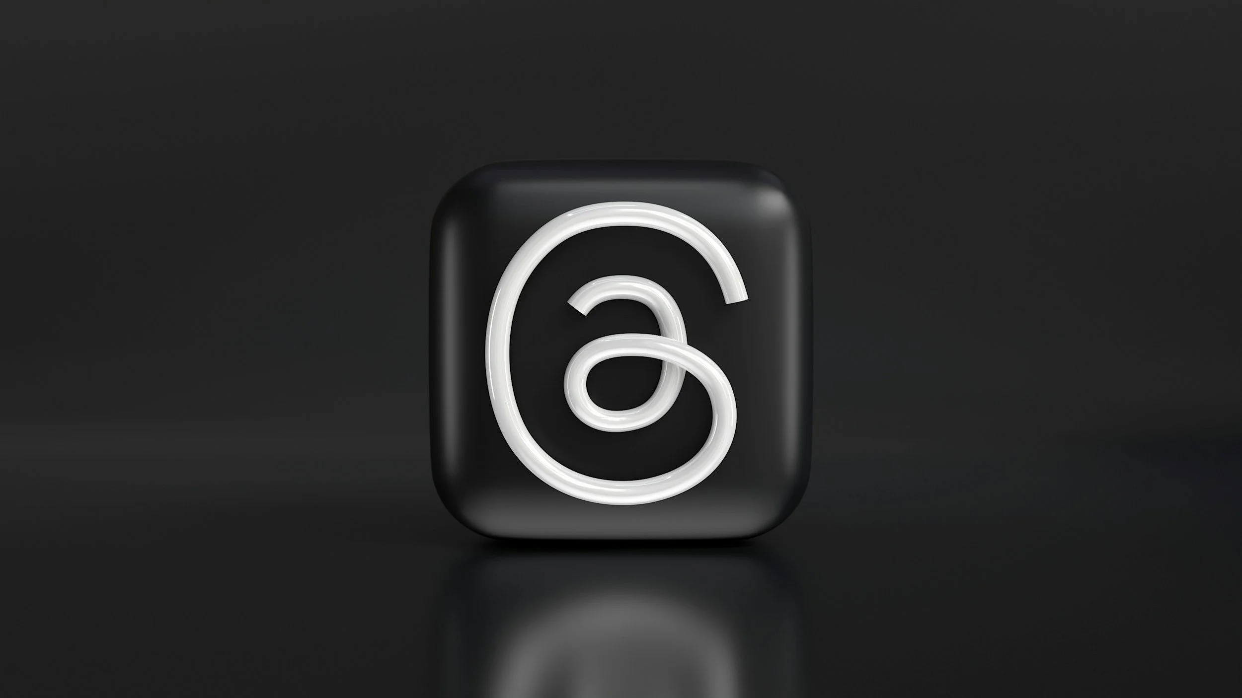 Neon sign in the shape of a lowercase 'a' with a white glow on a black background.