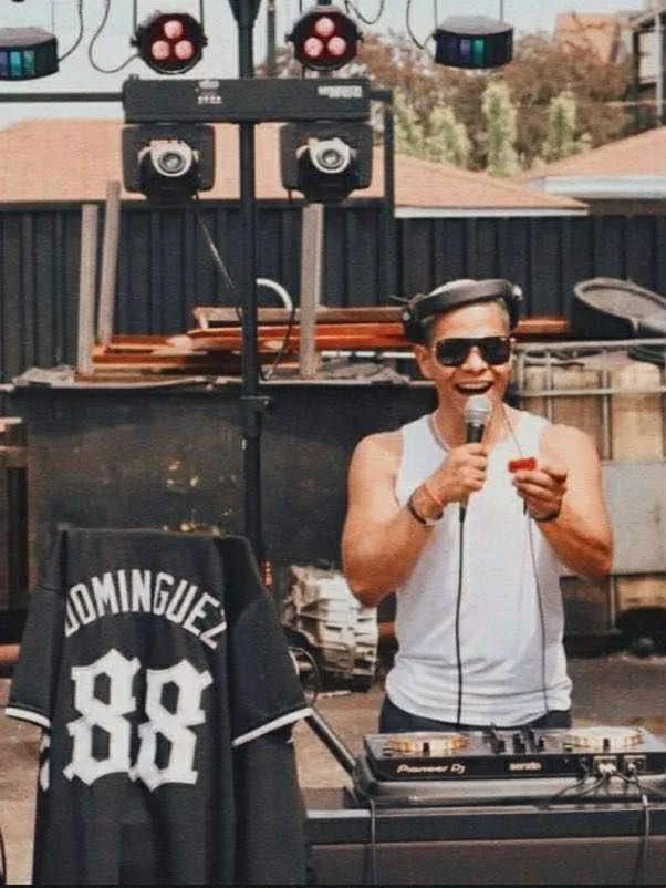 Bilingual DJ and emcee performing at a luxury Latin wedding with professional sound equipment and vibrant crowd interaction.