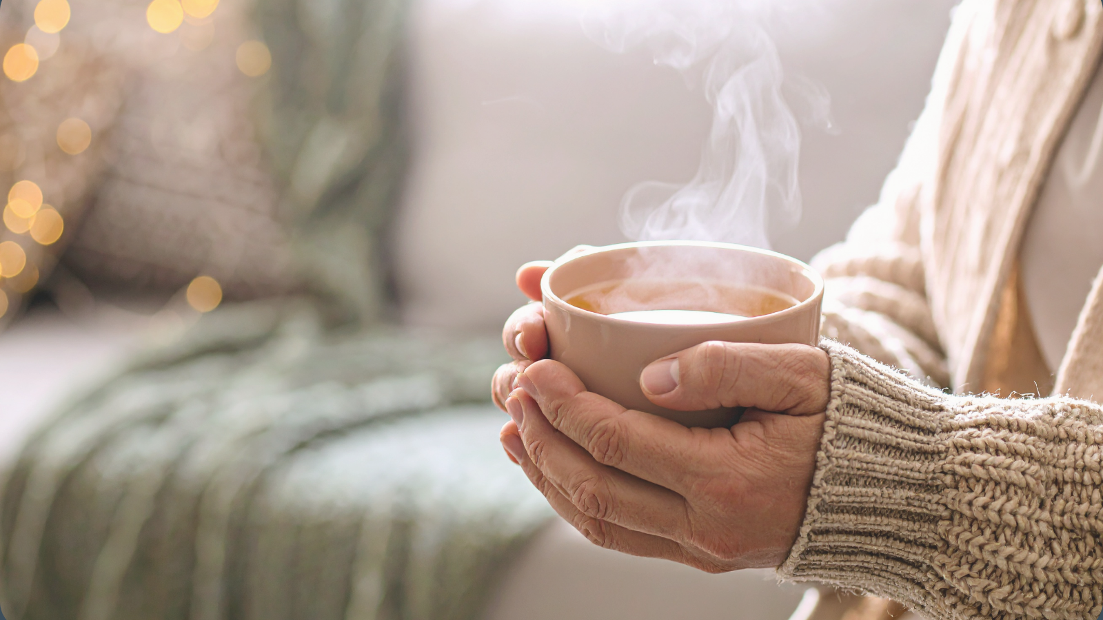 Hands holding a steaming cup of tea in soft light, symbolising nervous system relief, comfort, and gentle nourishment during overwhelm.