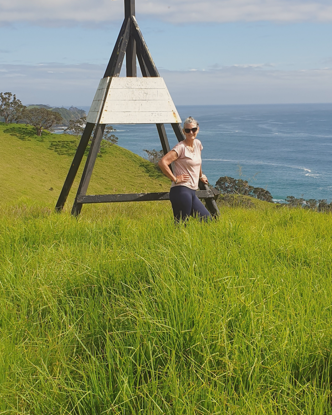 Jocelyn standing beside a mountain trig, symbolising perspective and clarity for sensitive, high sensation-seeking women learning about their dual wiring.