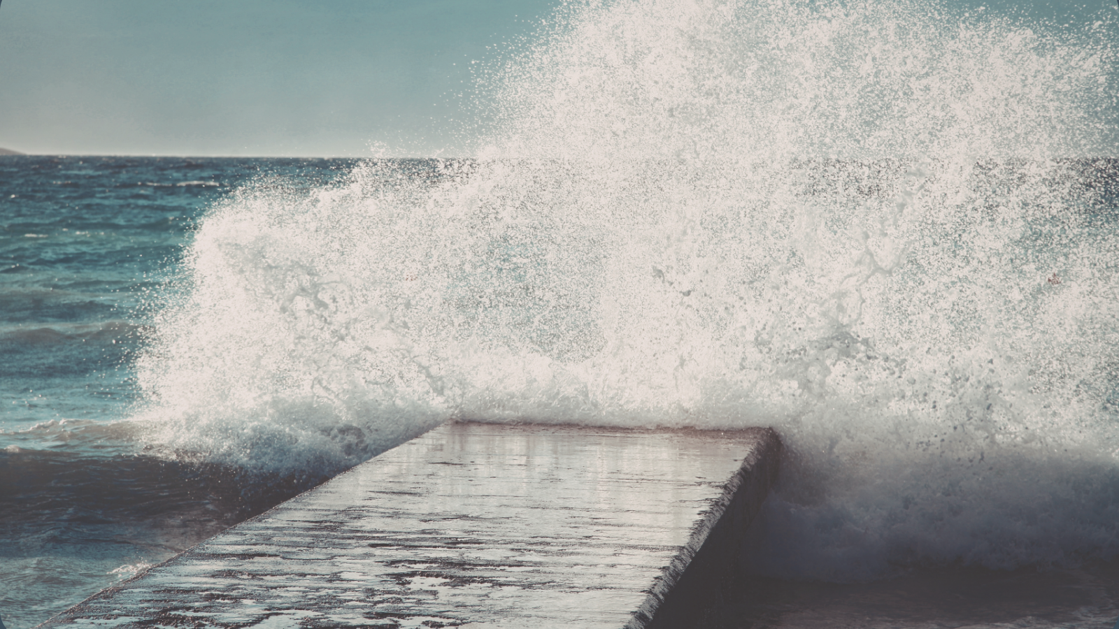 Wave crashing over a jetty, representing a tired but wired nervous system where rest doesn’t fully settle the body