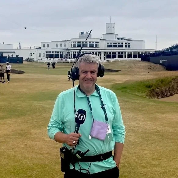 Dave Farrar of Speechless Media, outdoors with a microphone, commentating at a golf event.