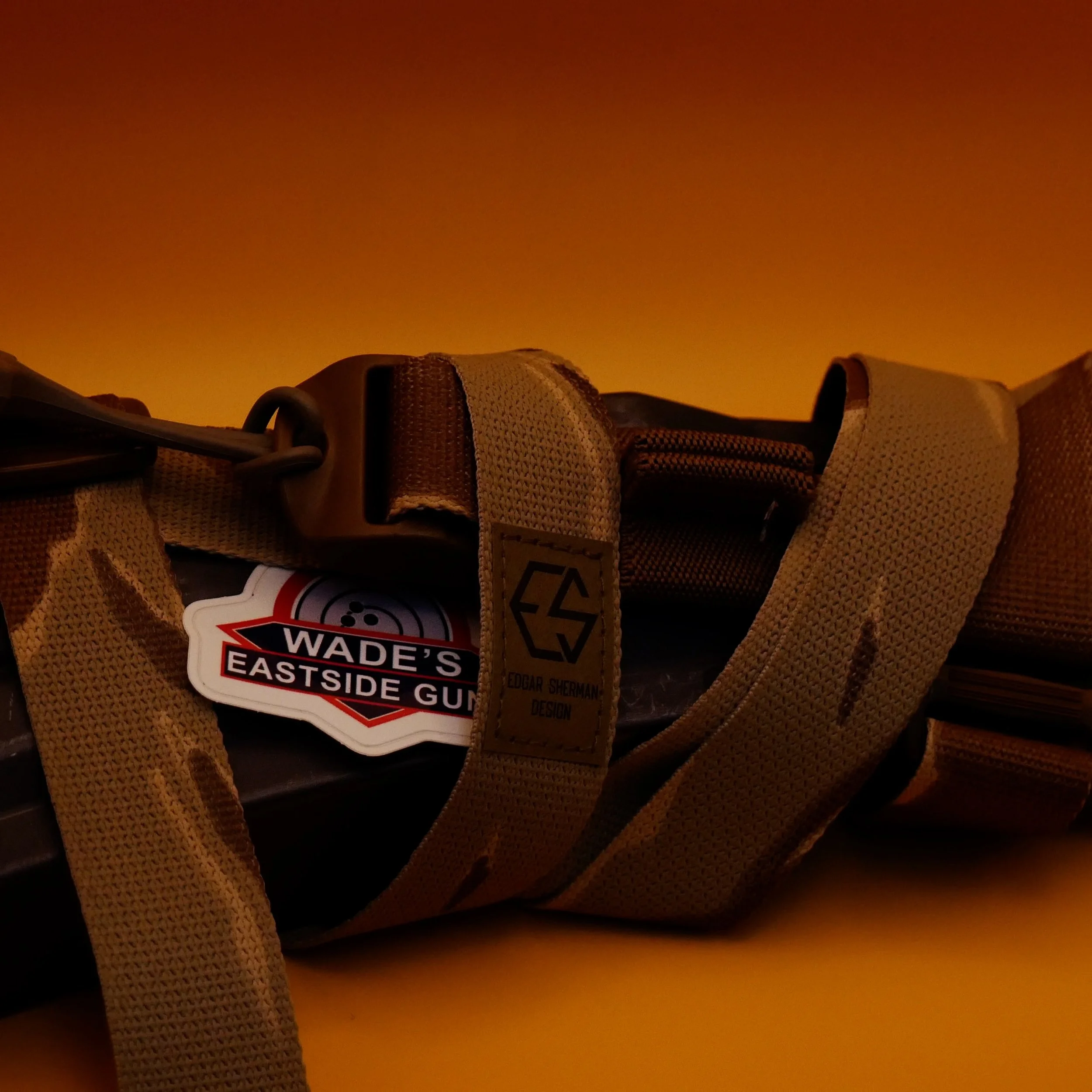 Close-up of a desert tiger stripe Edgar Sherman Design tactical gun sling wrapped around a surefire d60 ar15 magazine with Wade's Eastside Gun Logo displayed on a yellow background.