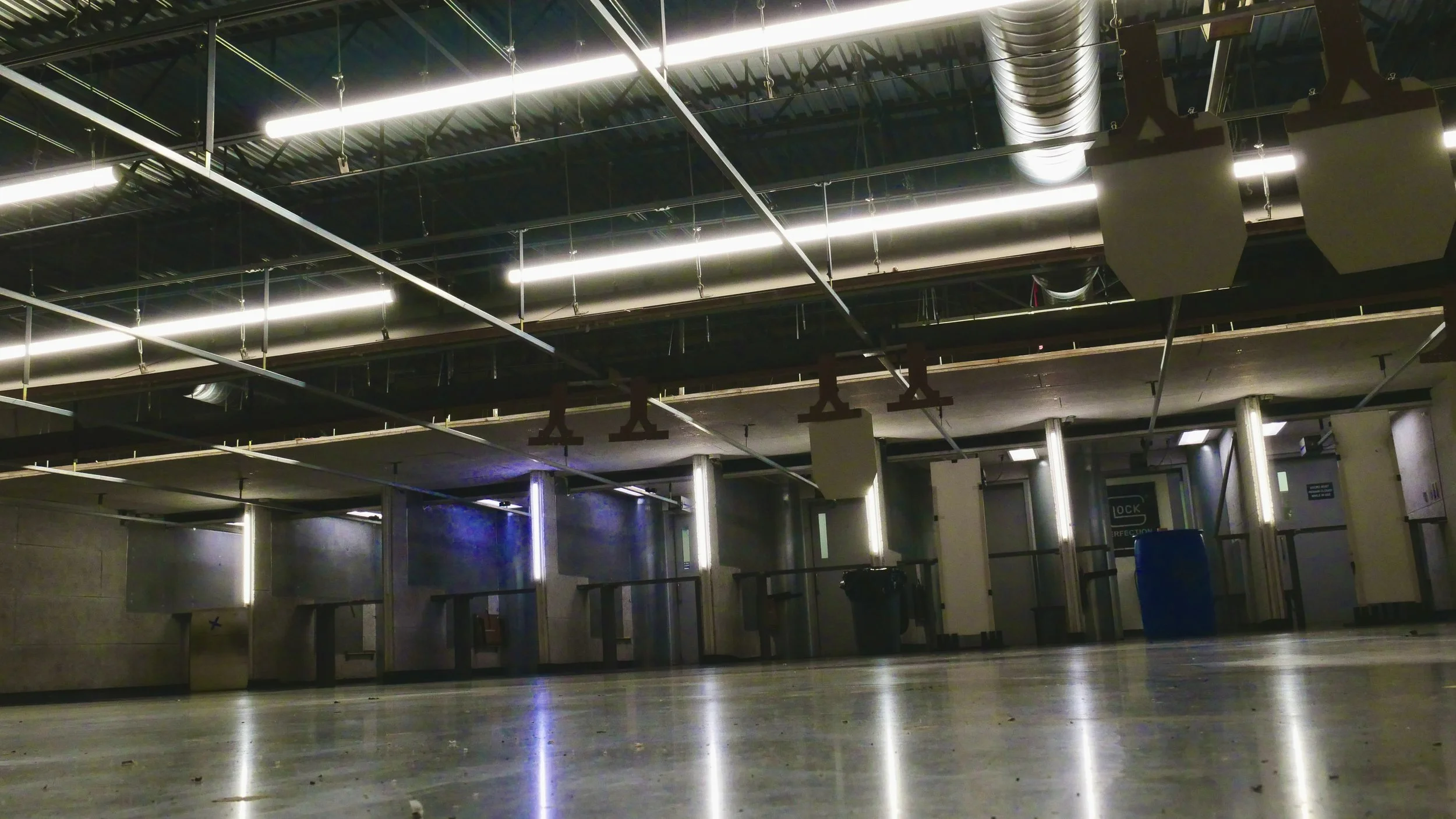 Empty shooting range with sound proofed ceilings and private booths facing the viewer.