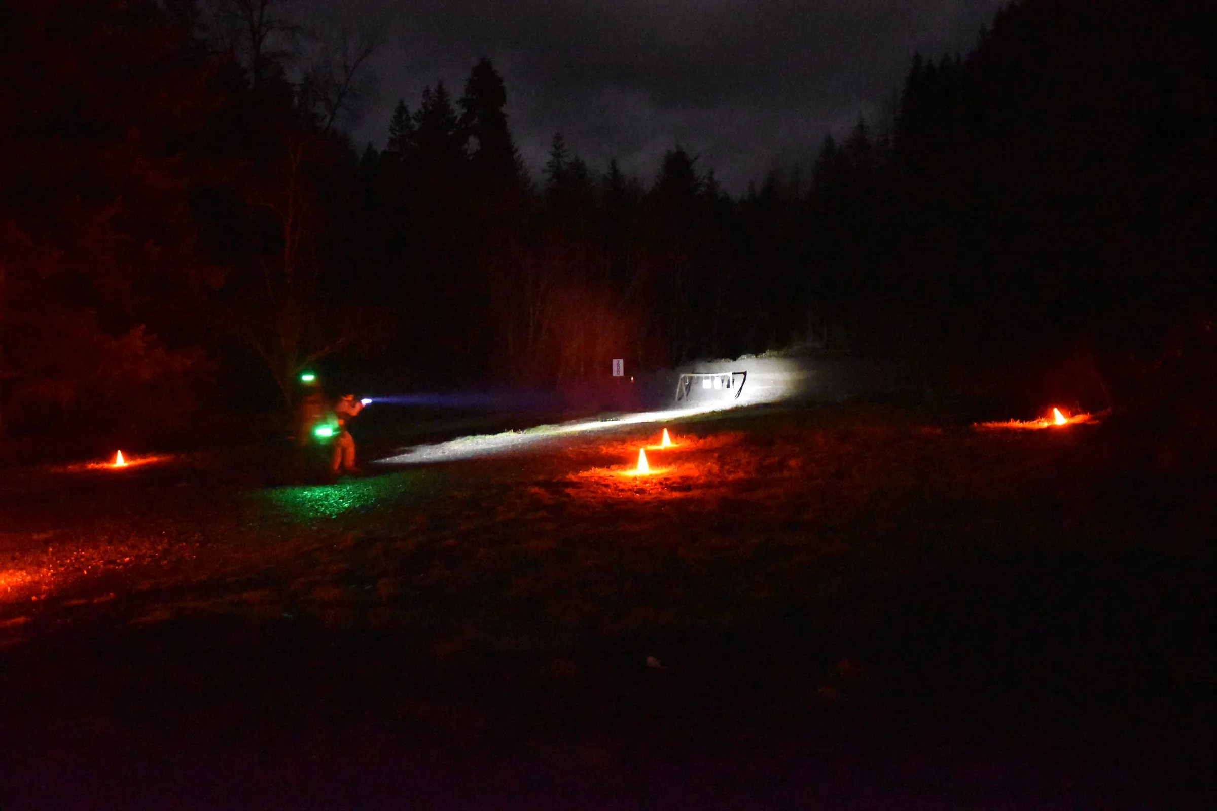 A nighttime scene showing a person with an ar15 rifle engaging a target in a low light environment. At a Washington state night time shooting competition.