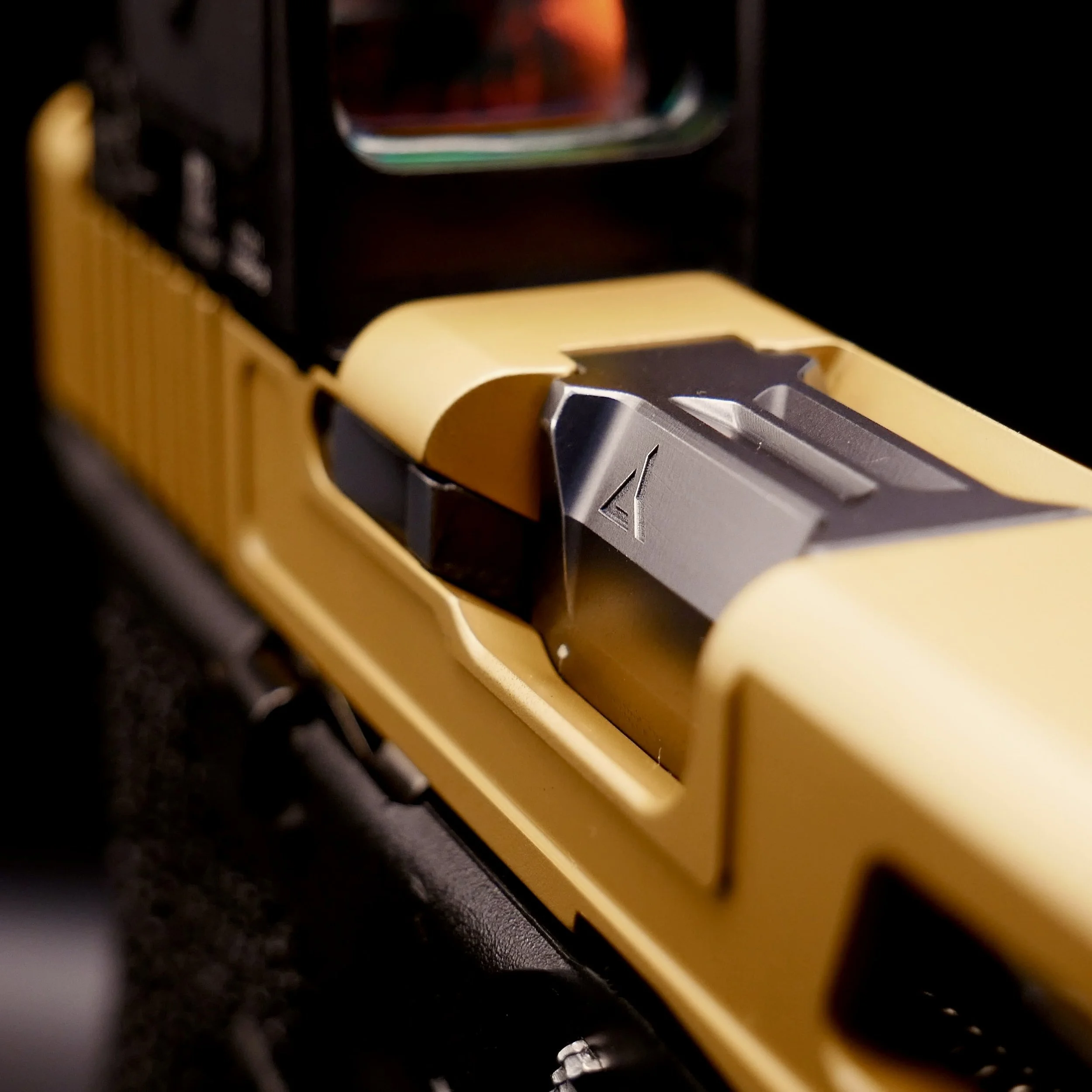 Close-up of a yellow gold Cerakote custom Glock 17 with a radian ramjet barrel and a Trijicon RCR.