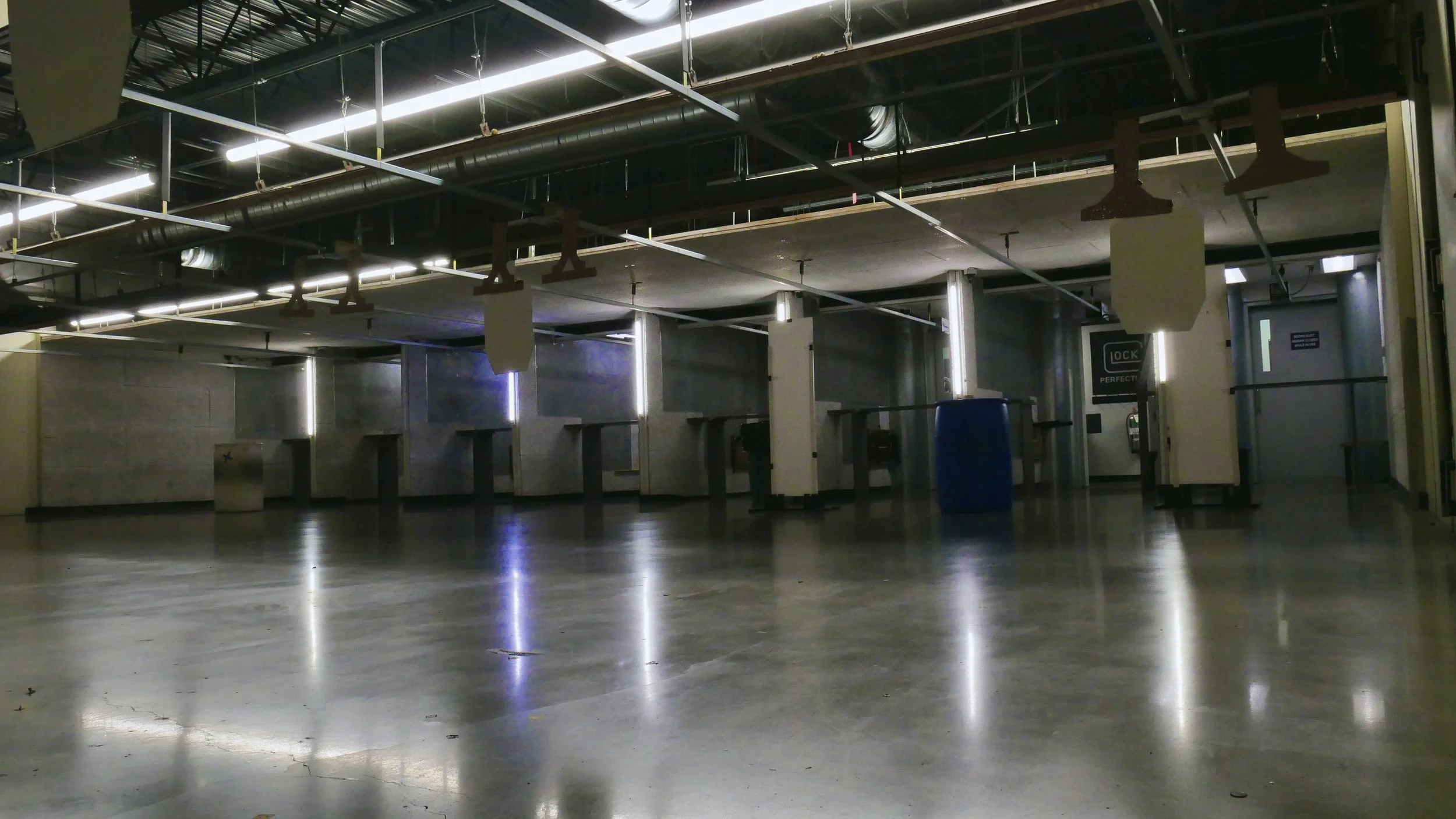 View of a shooting range from the perspective of the range itself. The view shows the front end of the private shooting booths at an indoor range and the polished concrete floor.