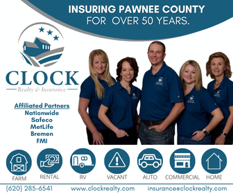 Group of five people standing together, smiling, in front of a banner that reads "Insuring Pawnee County for Over 50 Years." The banner features the clock logo of a realty and insurance agency called Clock Realty & Insurance, with affiliated partners