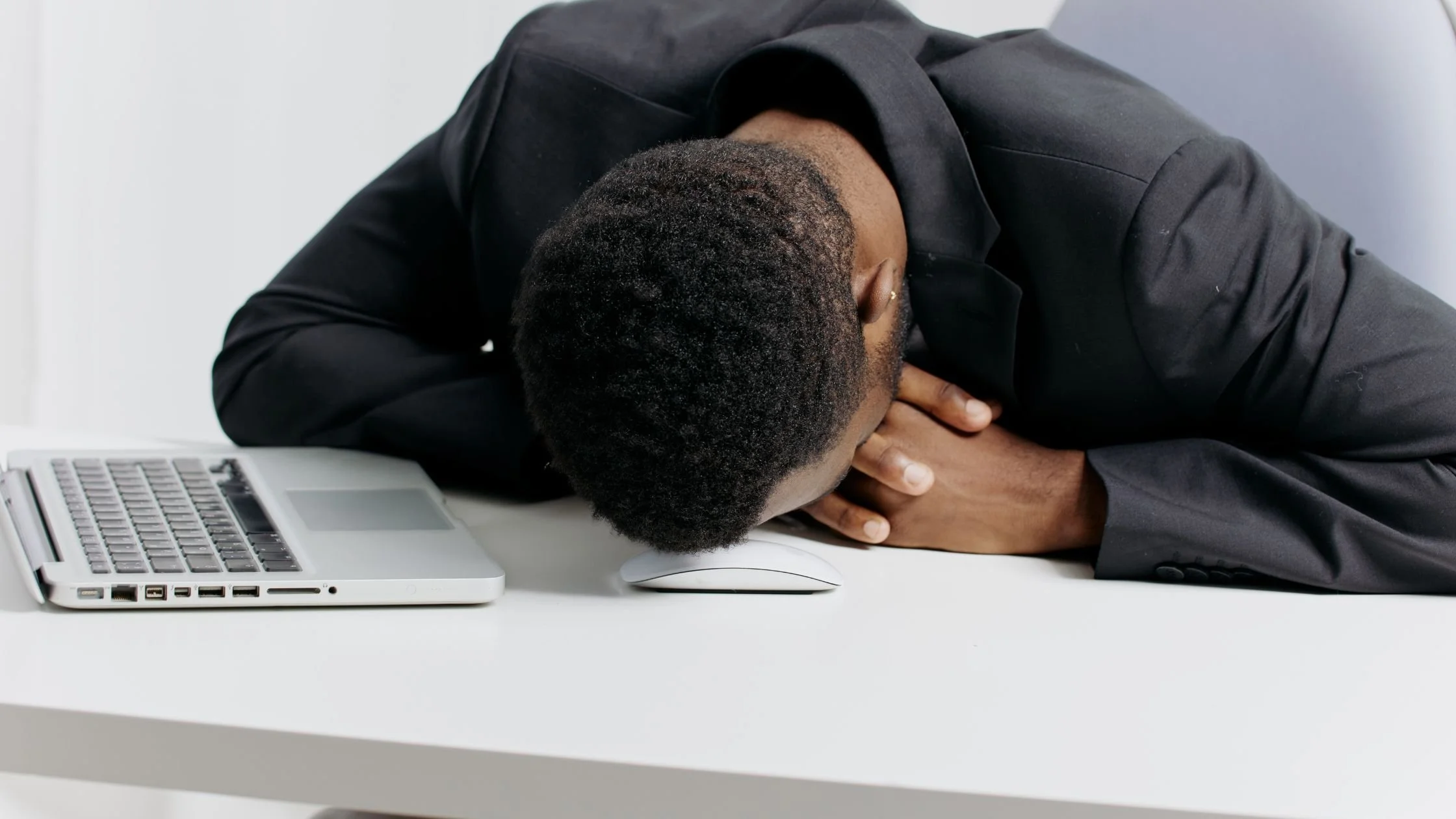 Exhausted employee resting head on desk next to a laptop