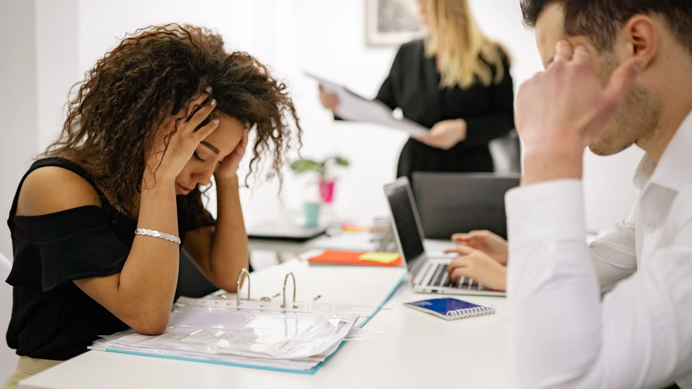 Stressed coworkers with hands on their heads during a work meeting