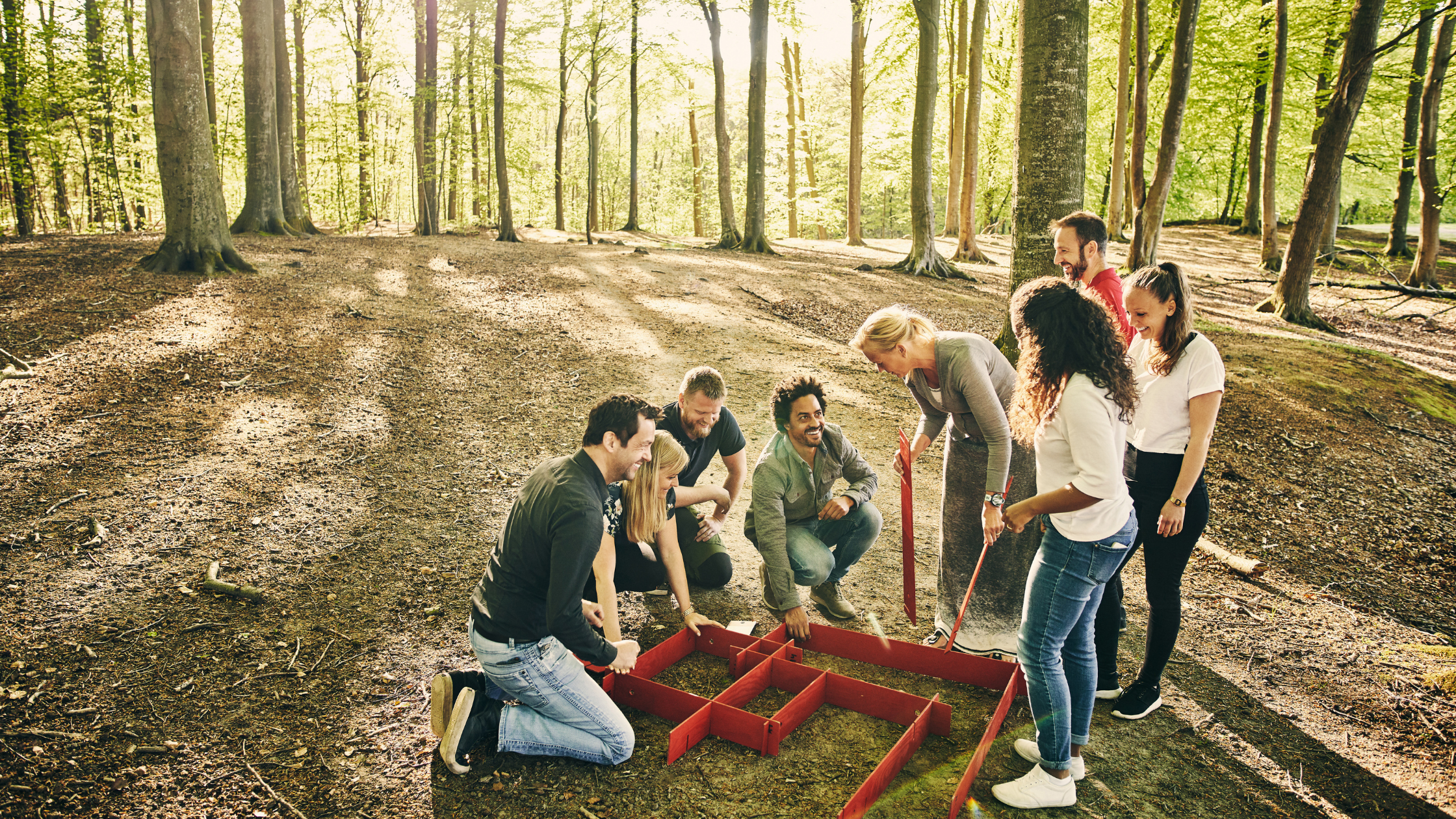 Colleagues collaborating on a team-building exercise outdoors in a forest, working together to solve a problem as a group