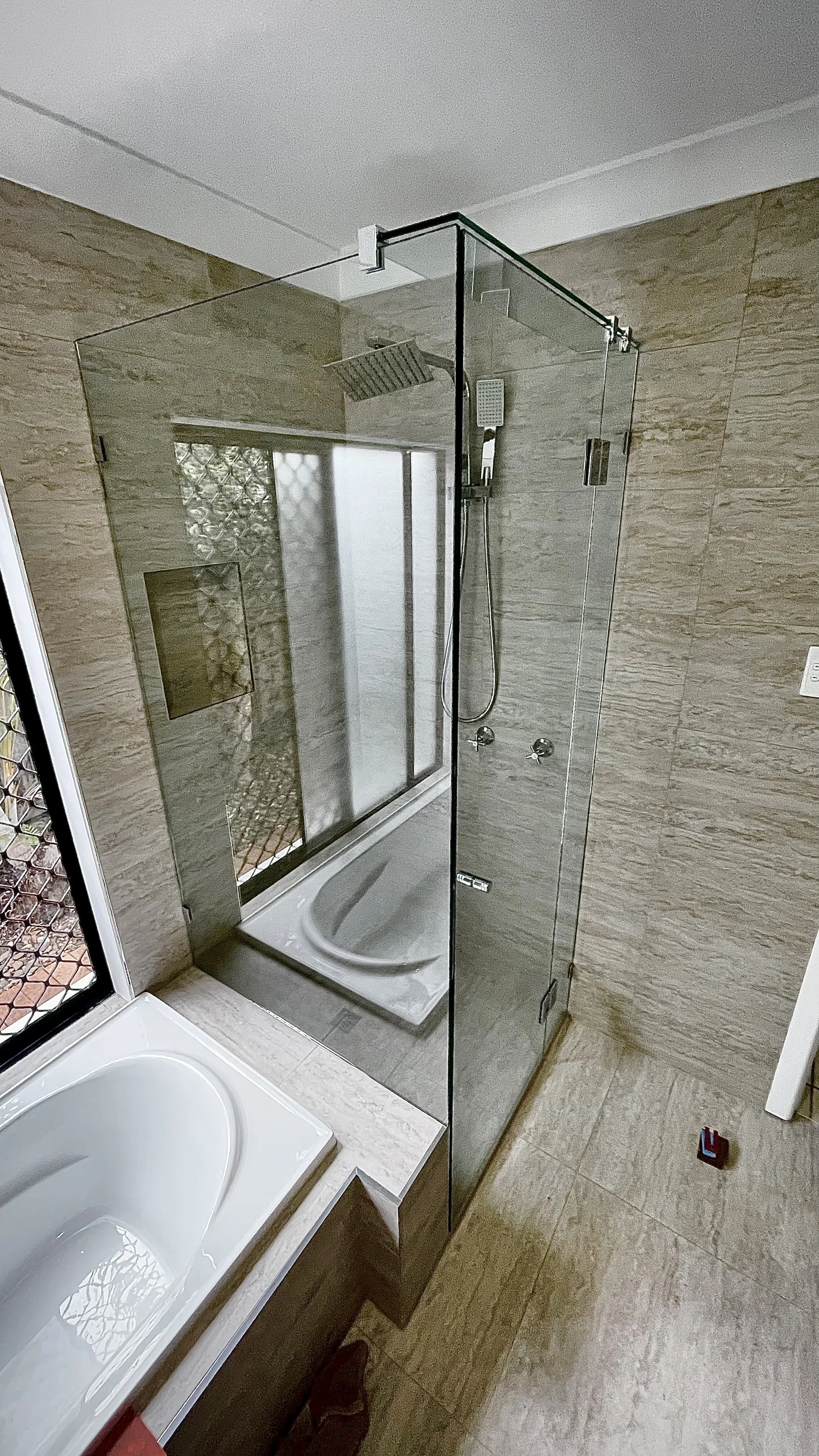Bathroom with a walk-in glass shower enclosure and a bathtub.