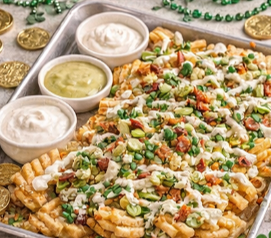 Sheet pan Irish-inspired nachos made with waffle fries, melted cheese, bacon, and green onions served with dipping sauces.