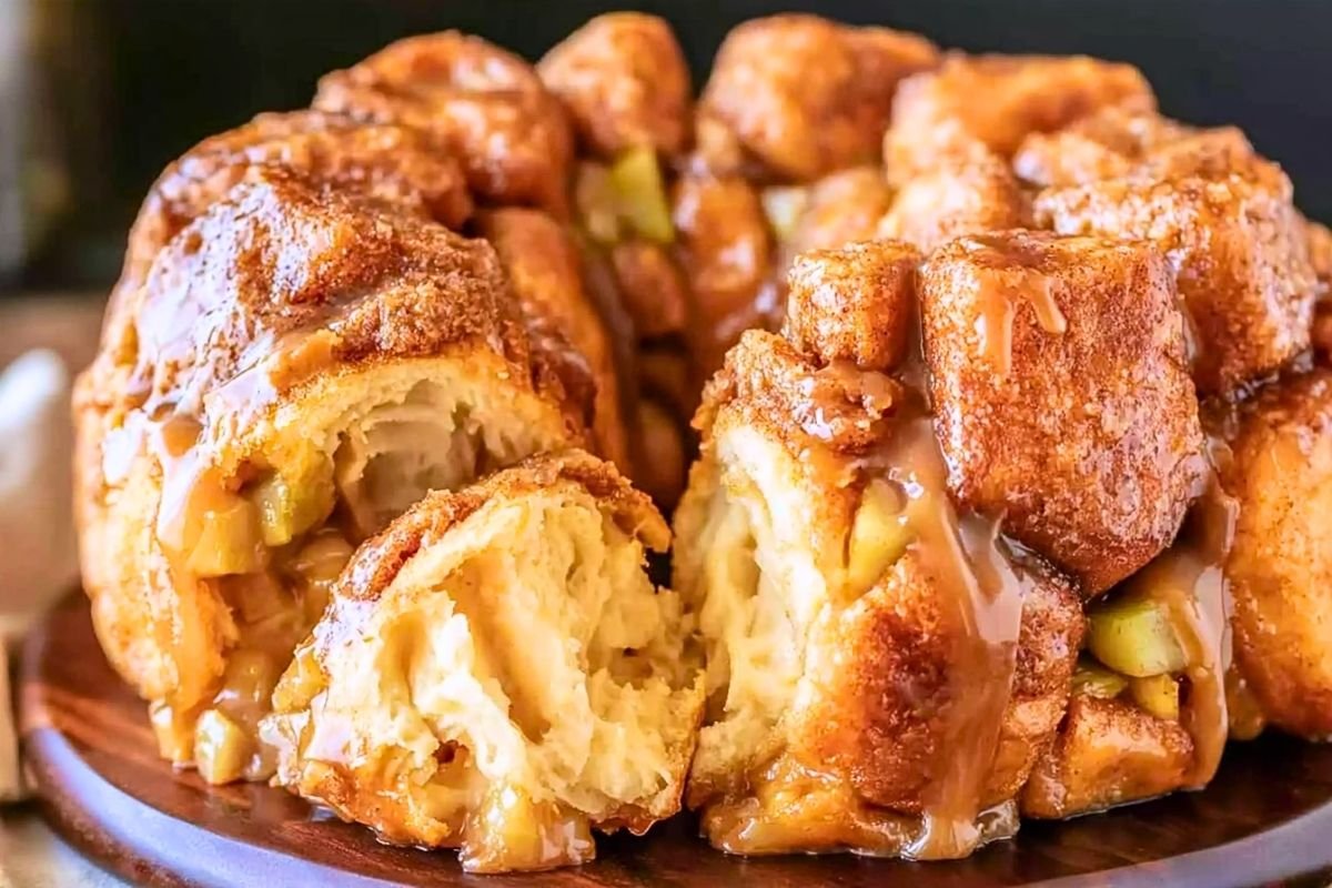 Pulled piece of apple monkey bread showing a fluffy, fully baked layered center with caramel on the edge