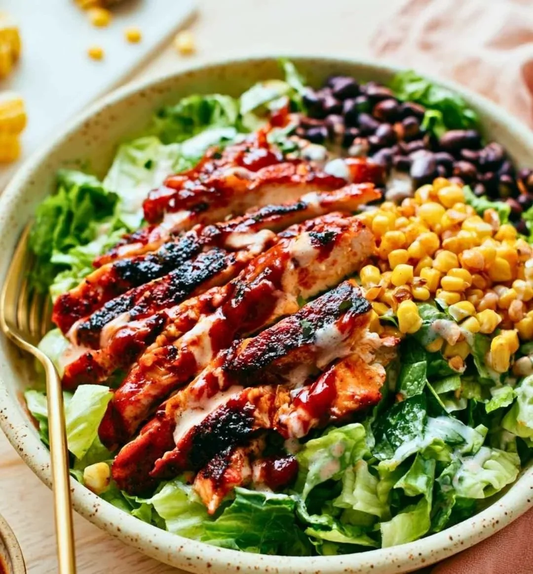 BBQ chicken salad with grilled chicken, corn, black beans, and ranch in a speckled ceramic bowl.