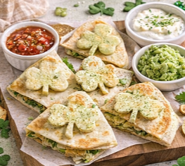 Cheese quesadillas cut into shamrock shapes and served with salsa, sour cream, and guacamole for a kid-friendly St. Patrick’s Day meal.