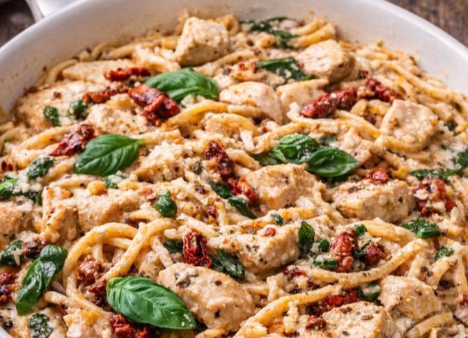 Creamy marry me dirty spaghetti with chicken, sun dried tomatoes, and parmesan in a white skillet, easy one pot budget dinner under $2 per serving