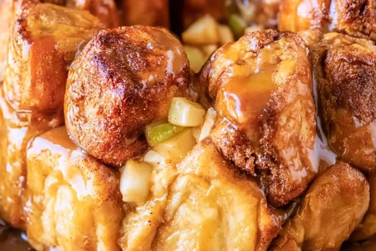 Apple monkey bread with canned biscuits on a plate, caramel dripping over cinnamon sugar pieces and diced green apples