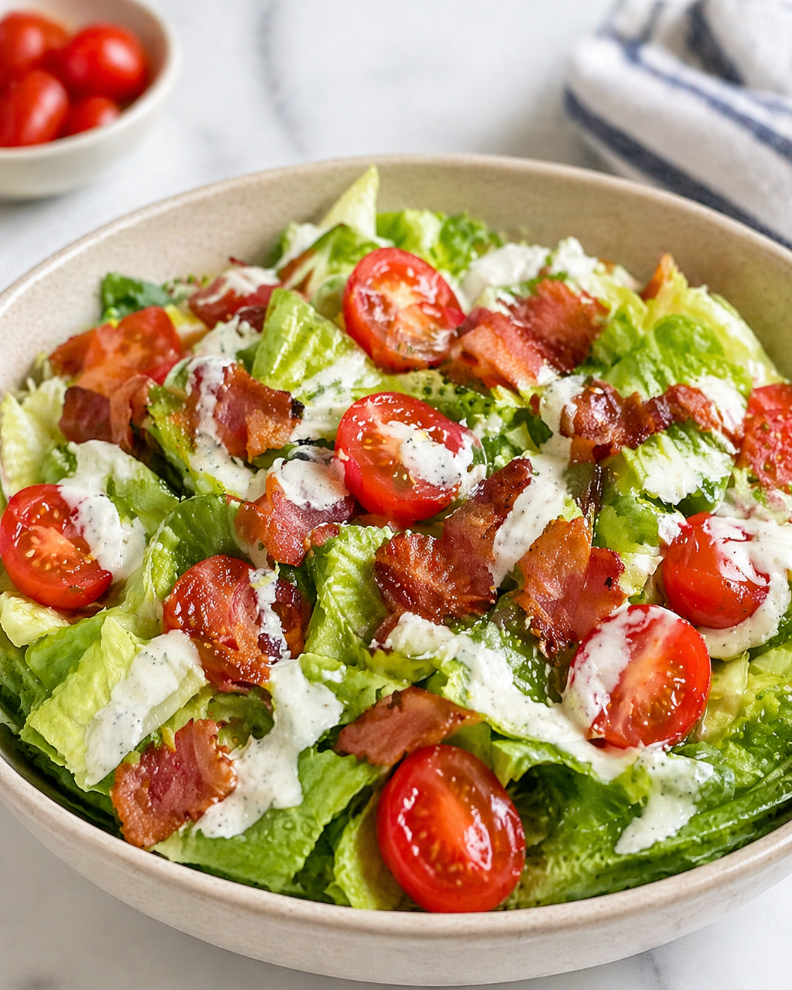BLT salad with crisp lettuce, cherry tomatoes, chopped bacon, and ranch dressing in a ceramic bowl