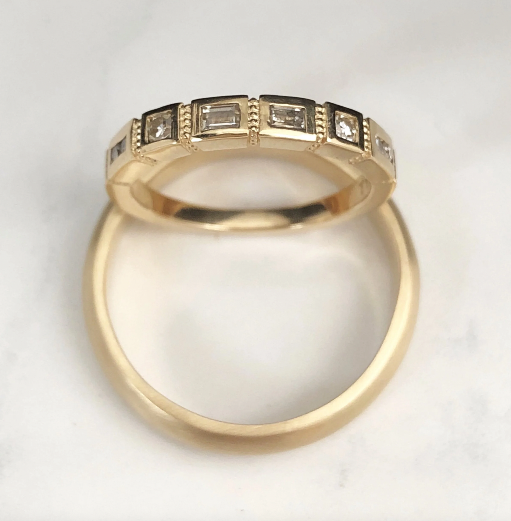 A gold ring with square and rectangular diamonds embedded along the band.