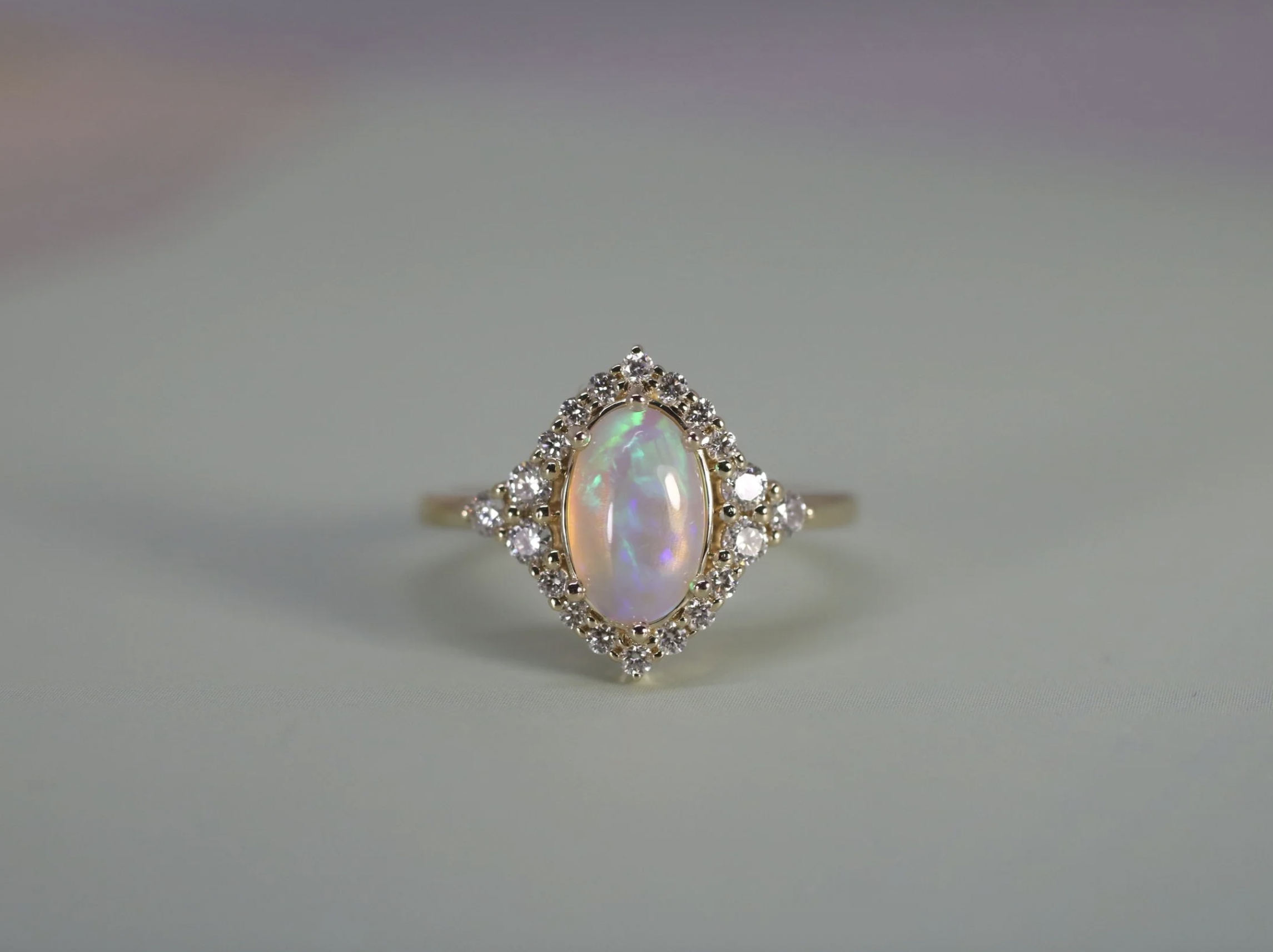 Gold ring with an oval opal gemstone surrounded by small diamonds.