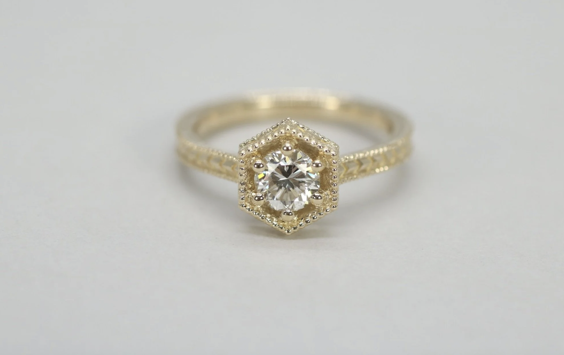 Gold ring with a central round diamond in a hexagon-shaped frame with small diamonds around it.