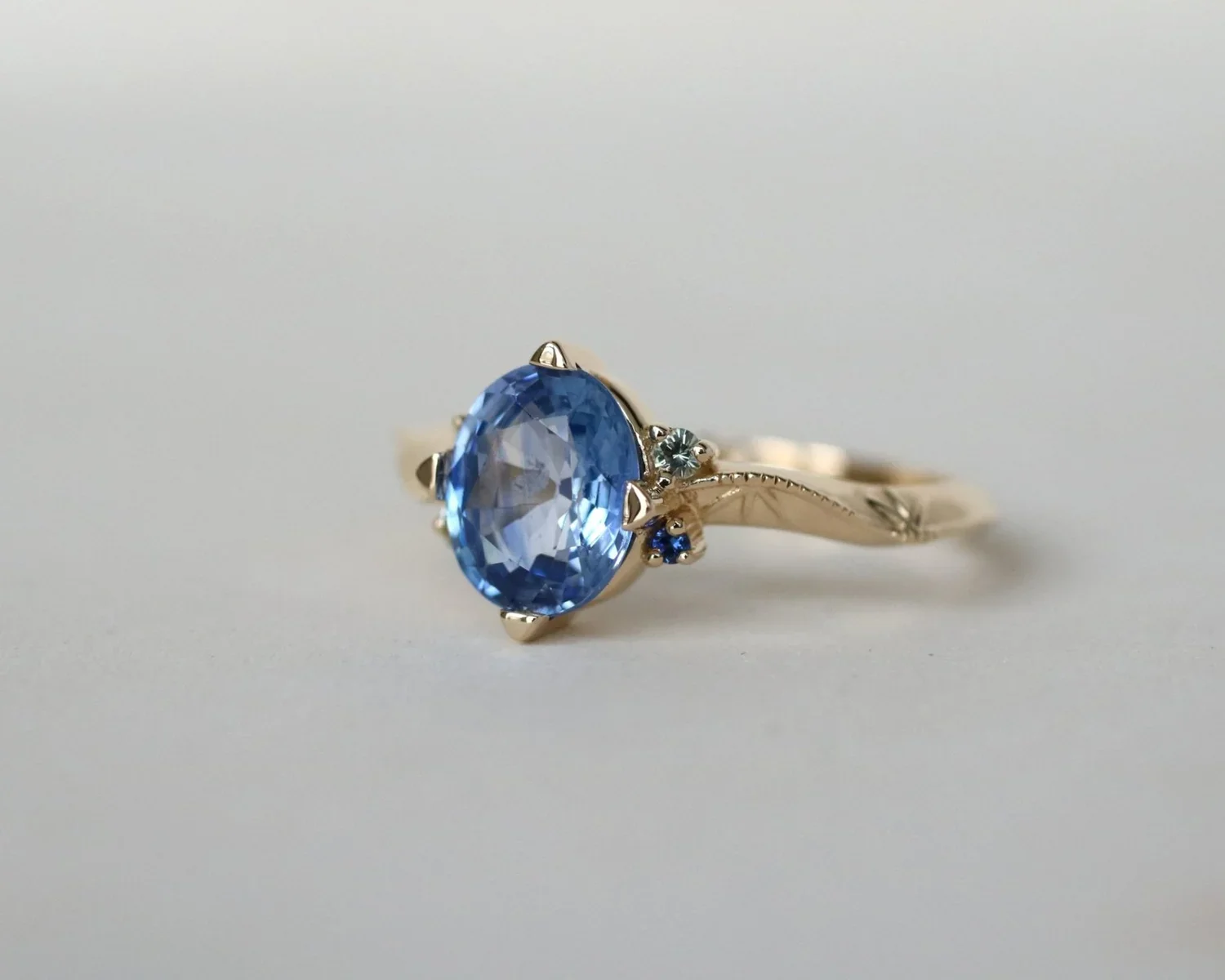 A gold ring with a large oval blue gemstone centerpiece and smaller blue and white stones on the band.