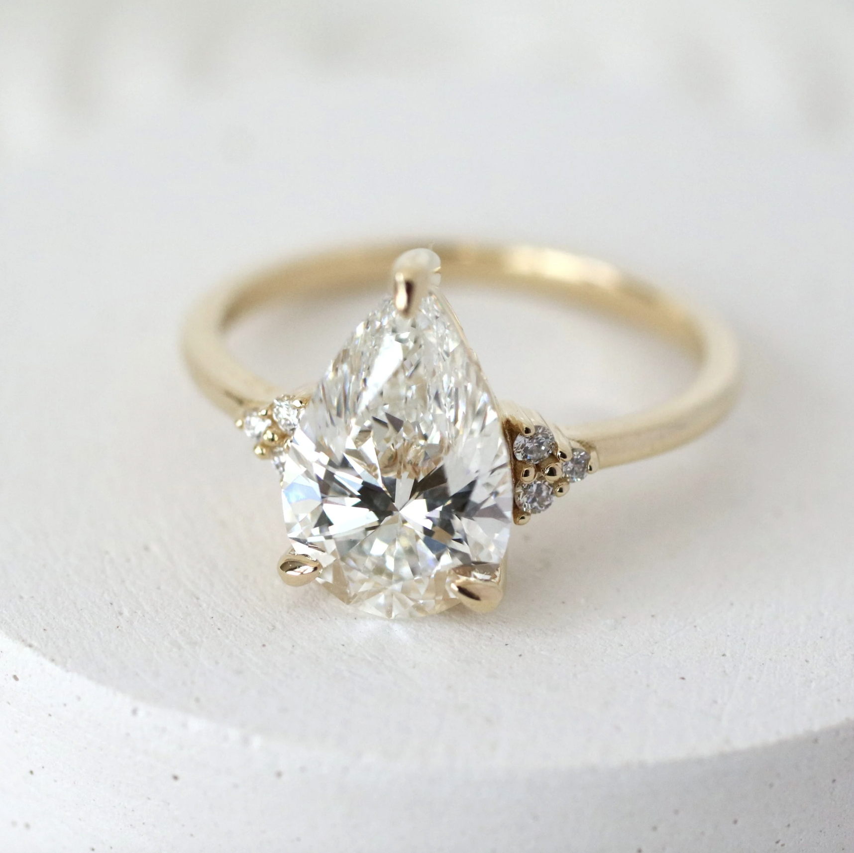 A gold ring with a large pear-shaped diamond and smaller diamonds on each side.