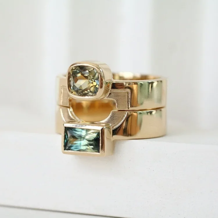 Gold rings with square and cushion-cut gemstones against a white background.