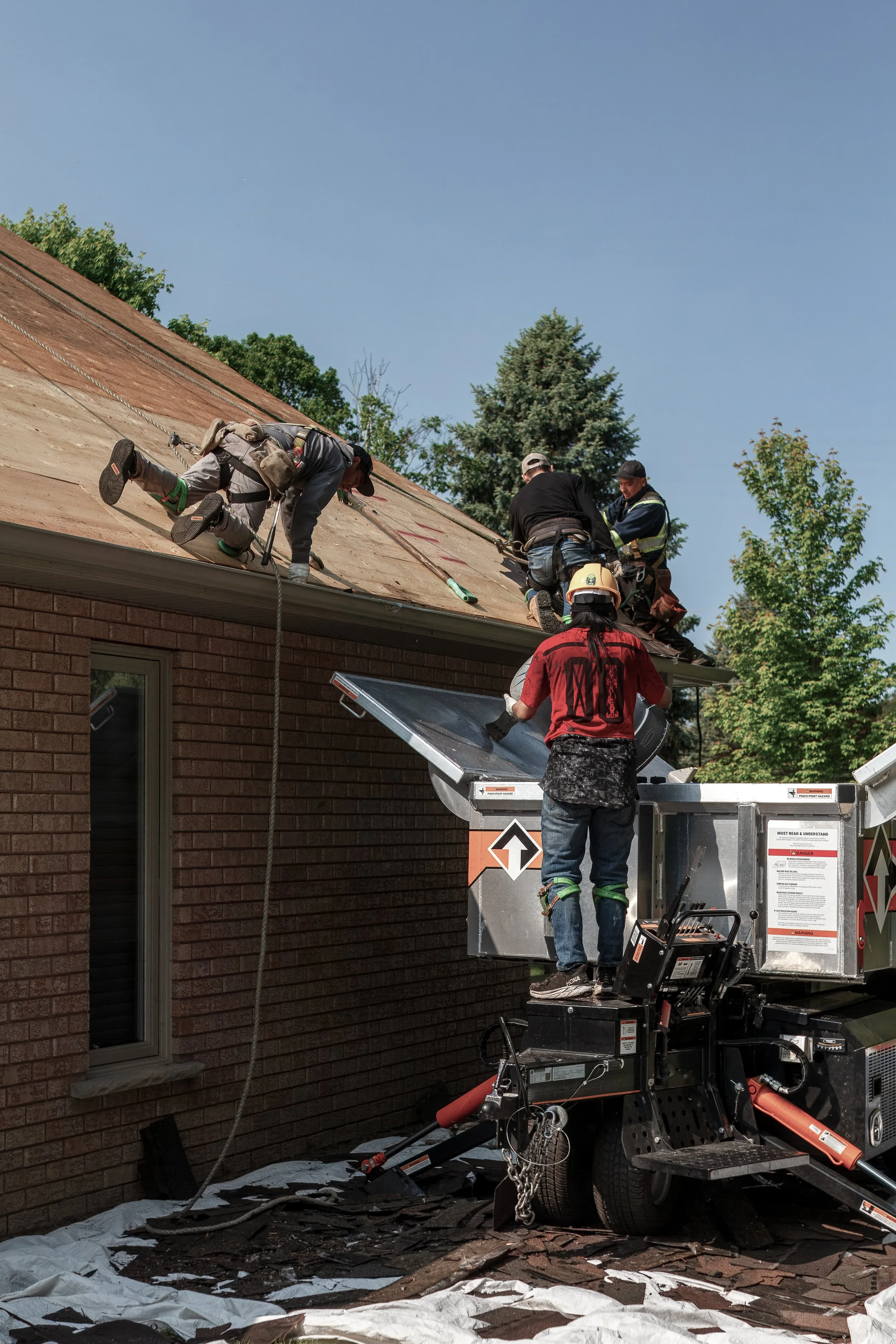 Workers on a roof and a platform removing or repairing the roof of a residential building during daytime.