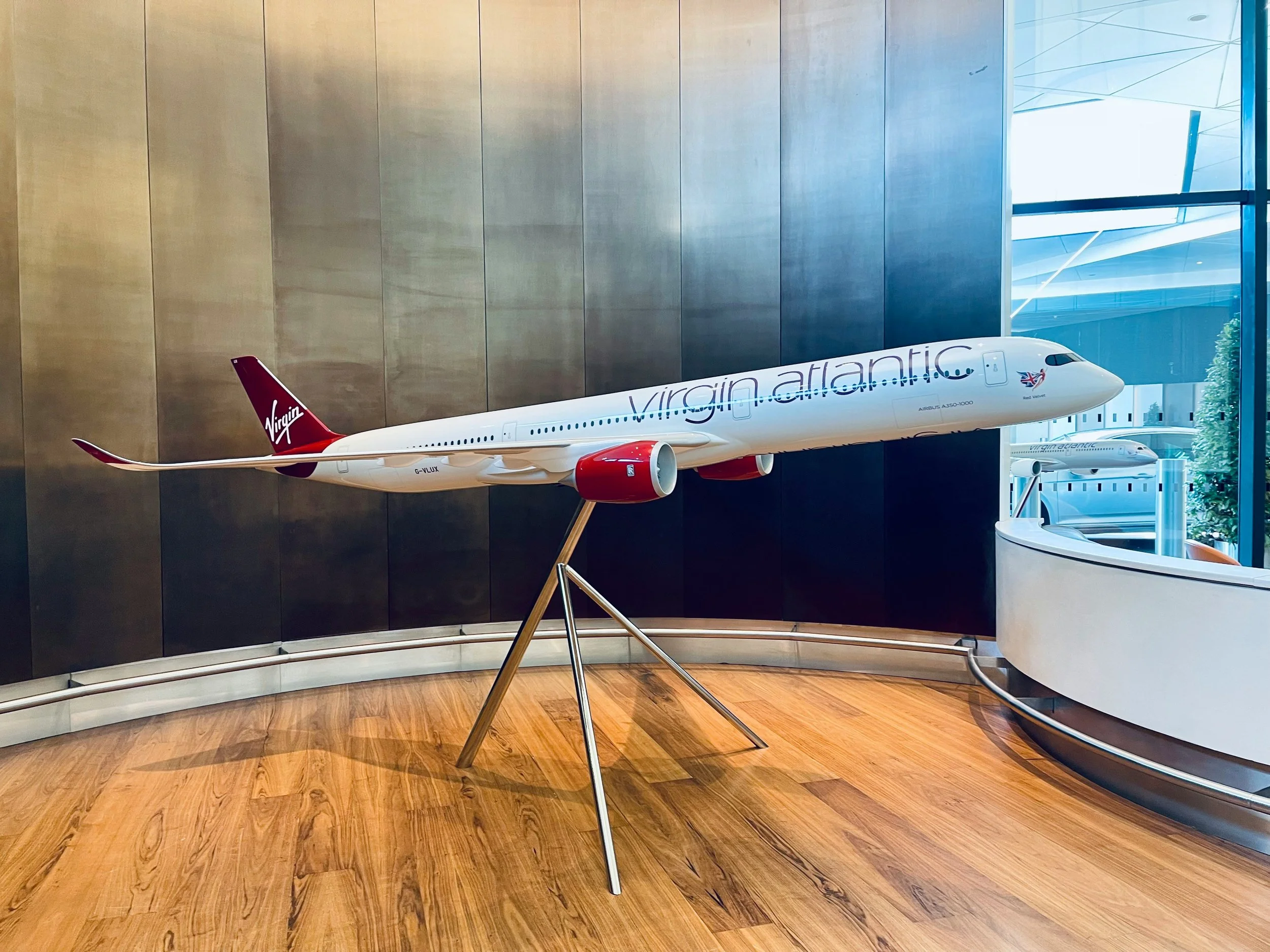 Model of a Virgin Atlantic airplane display inside a building with wood flooring and large windows.
