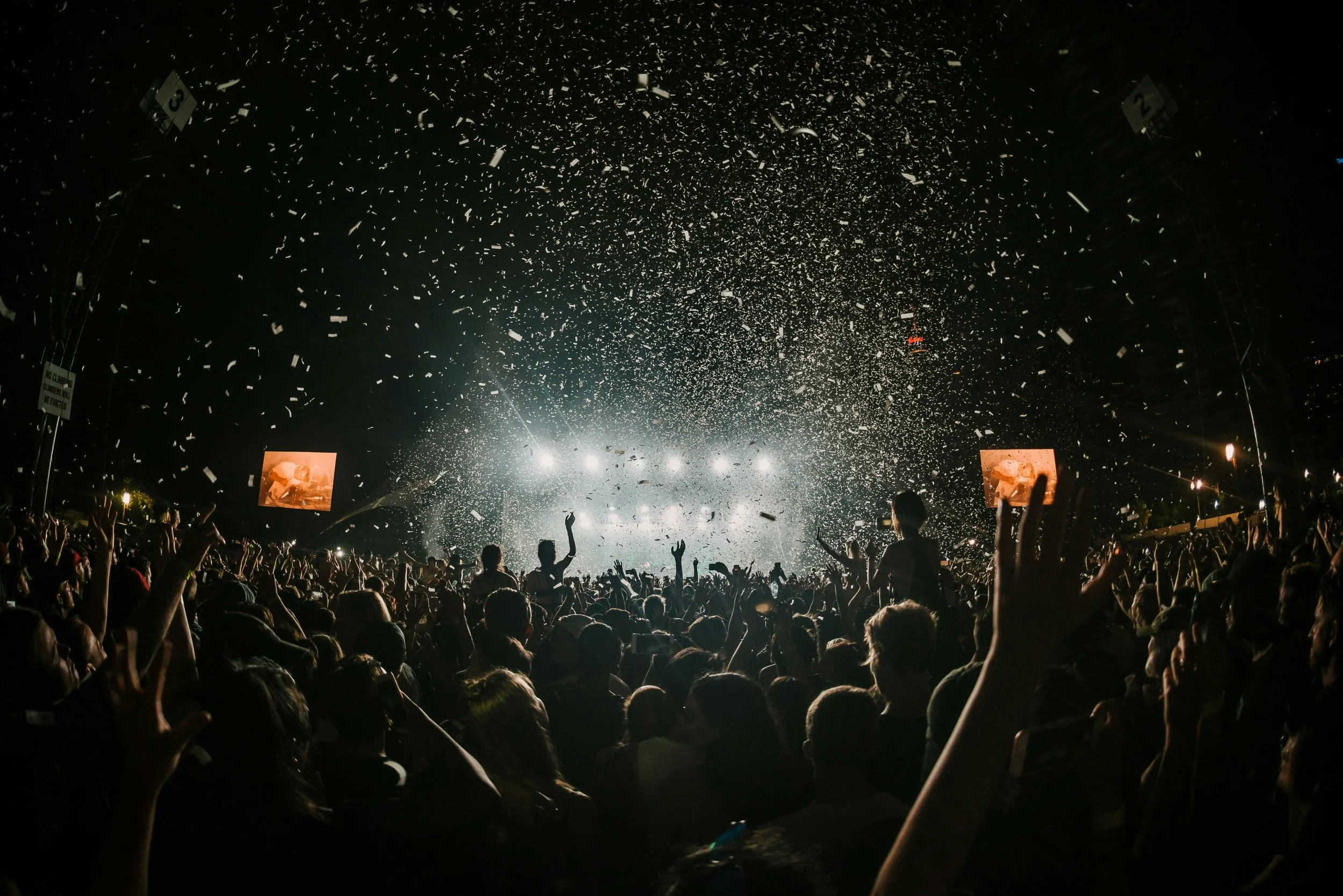 Crowd watching a concert at night with confetti falling and stage lights in the background. Curated Event Listings in Columbia, Maryland