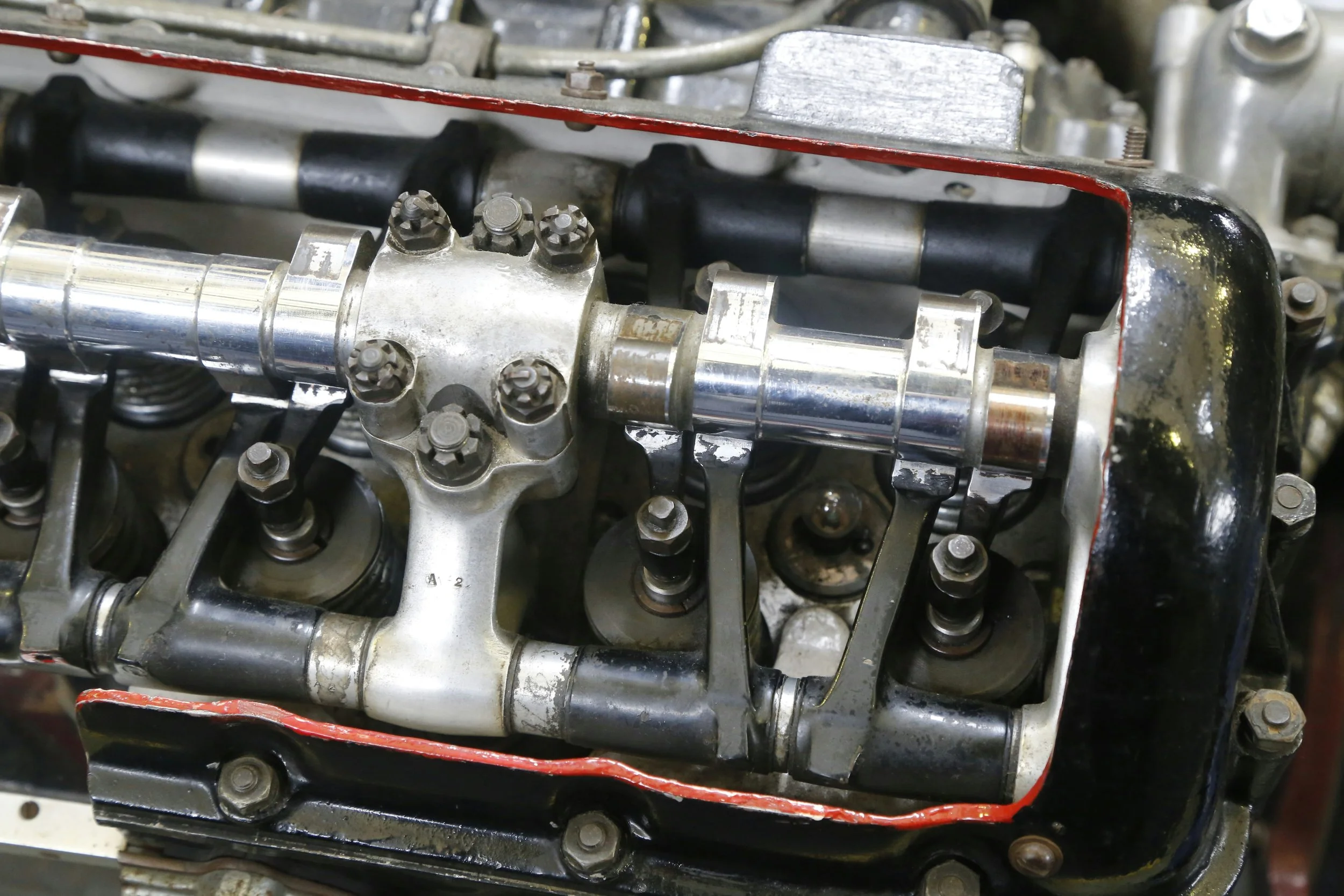 Close-up of a disassembled engine cylinder head with visible rocker arms, valve springs, and a camshaft.