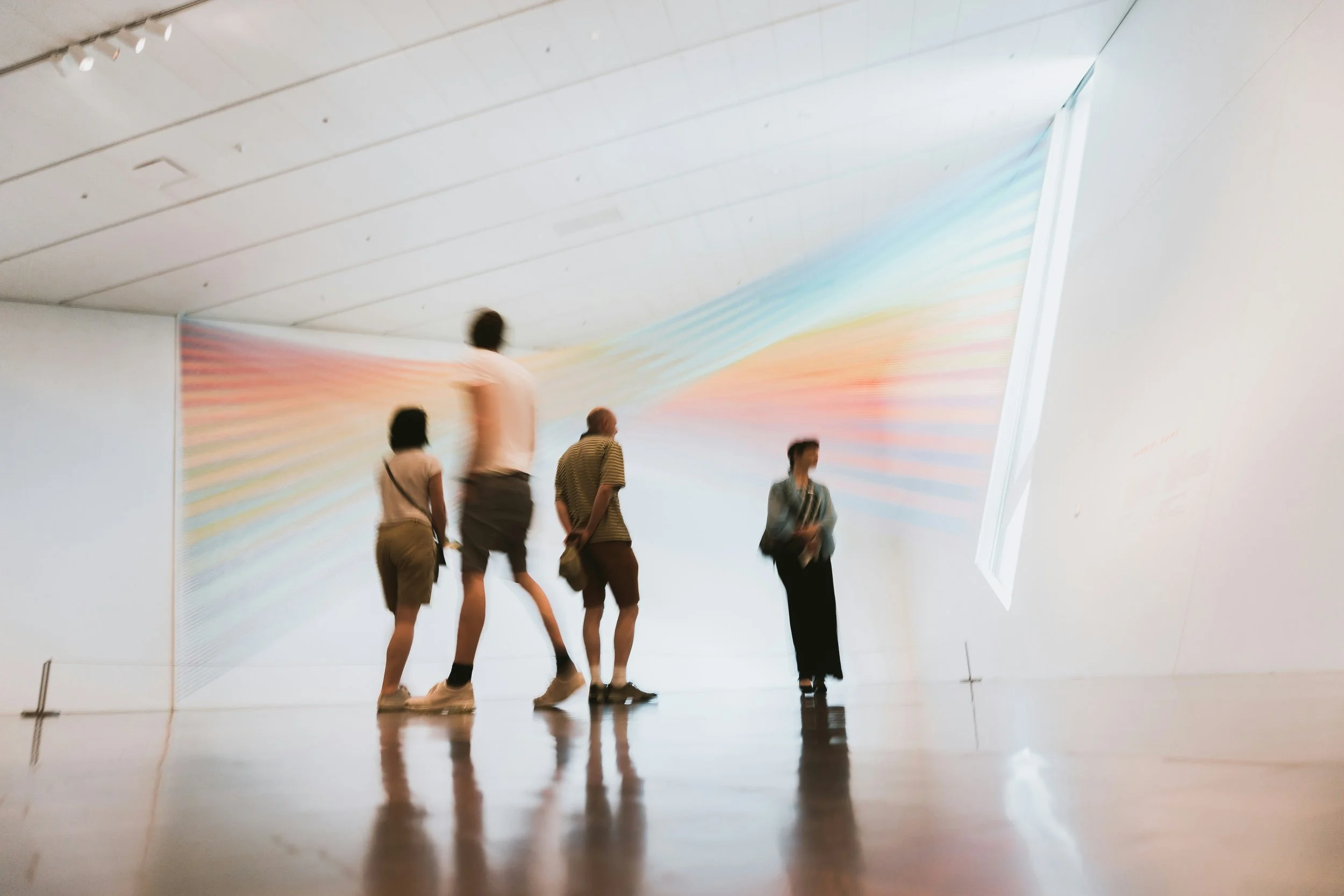 Group of five people in a modern art gallery looking at a colorful, abstract digital display on a wall. Curated Event Listings in Columbia, Maryland