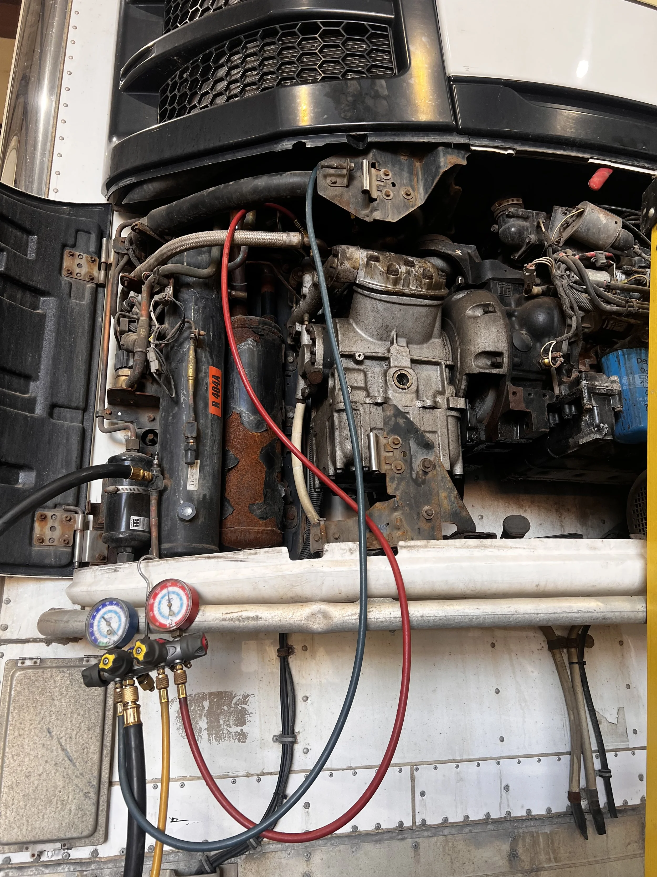 A close-up of an engine being serviced with gauges, hoses, and tools connected for maintenance or repair.