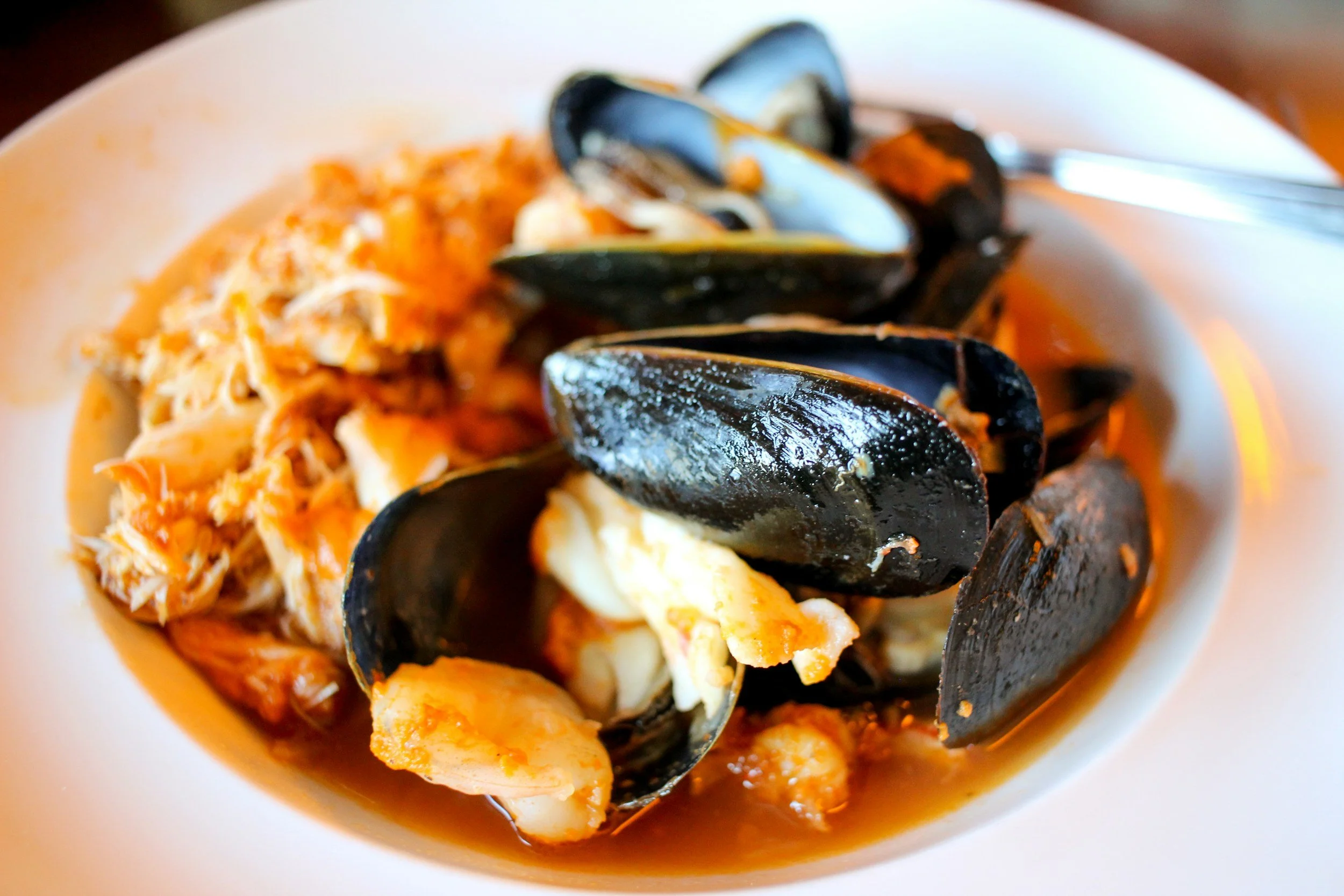 Seafood dish with mussels, crab meat, and possibly other shellfish in a bowl.