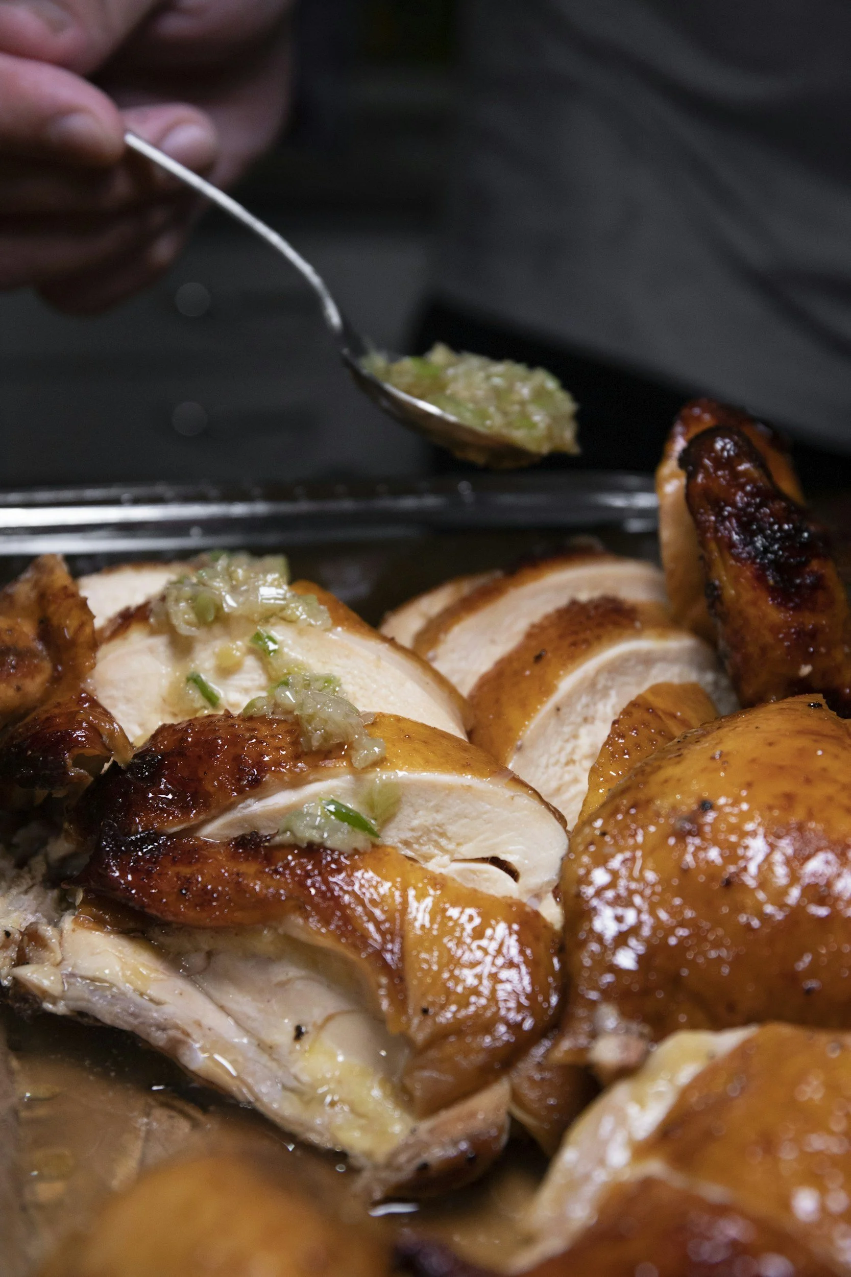 Close-up of cooked turkey with stuffing and gravy, with a hand adding stuffing from a spoon.
